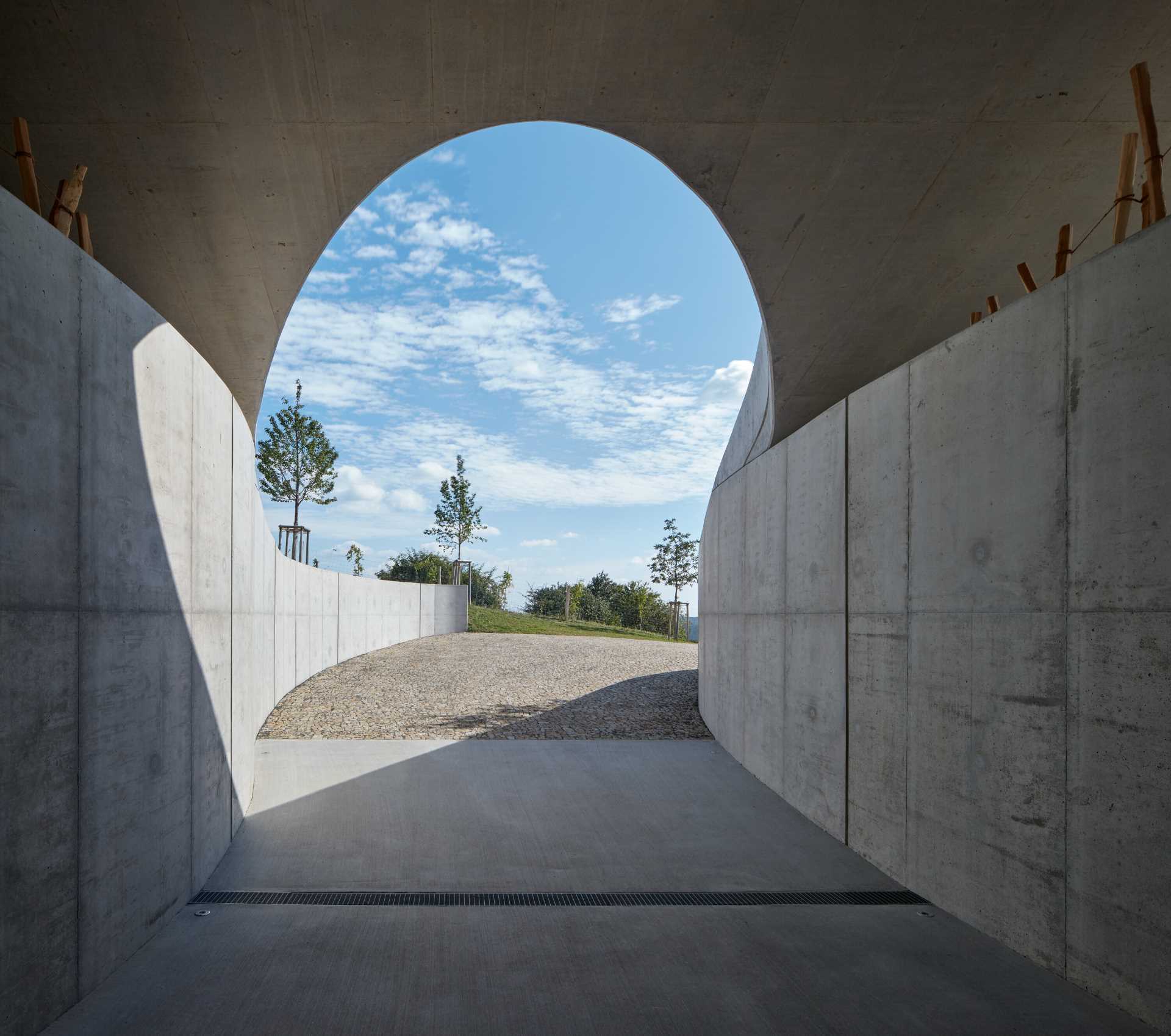 A modern winery that uses exposed concrete, glass, metal, oak, and acacia wood to support the organic form of the building.