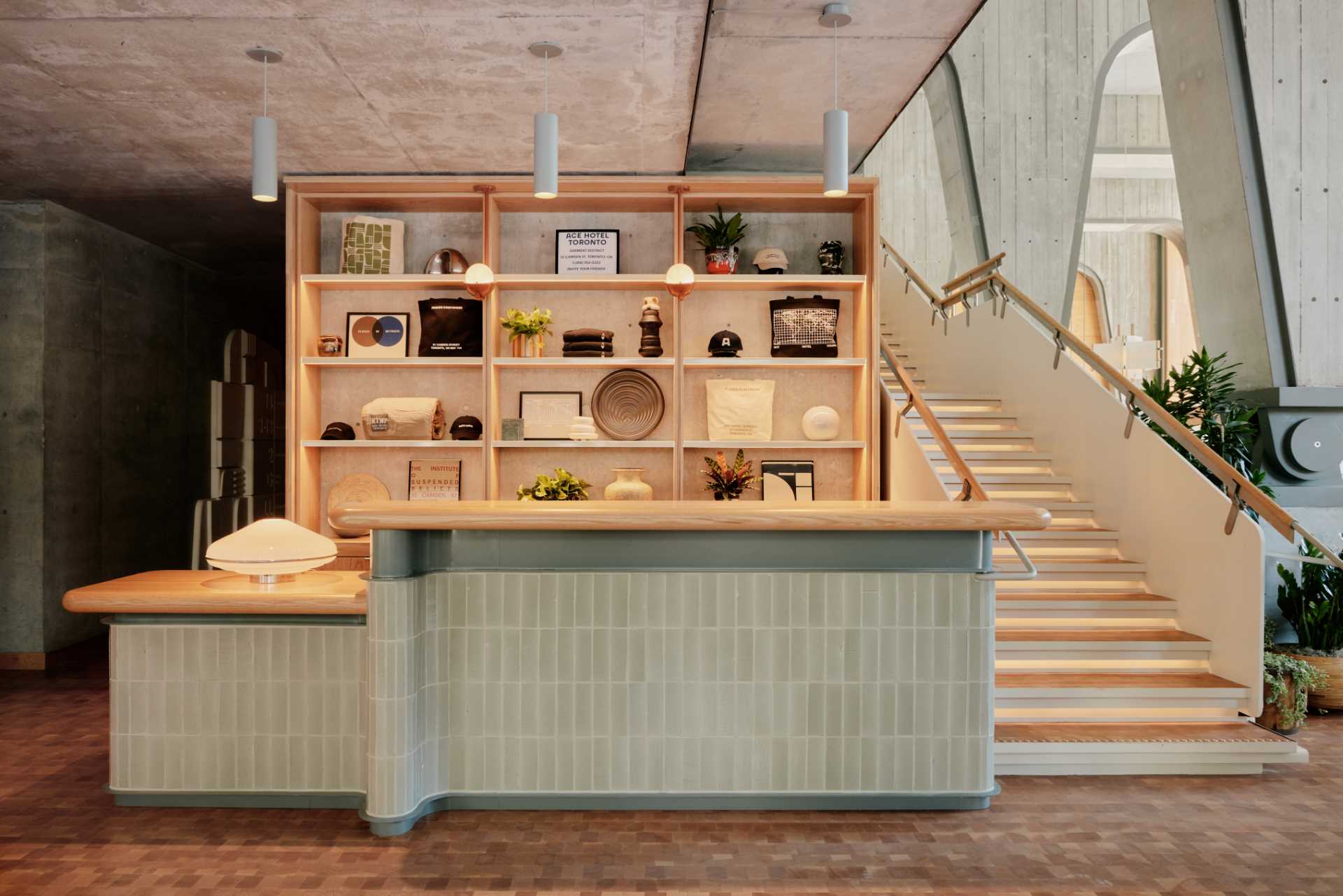 This modern hotel lobby has a welcoming design, with pale green tiles that clad the reception desk, while the wood countertop and shelving complement the nearby stairs.