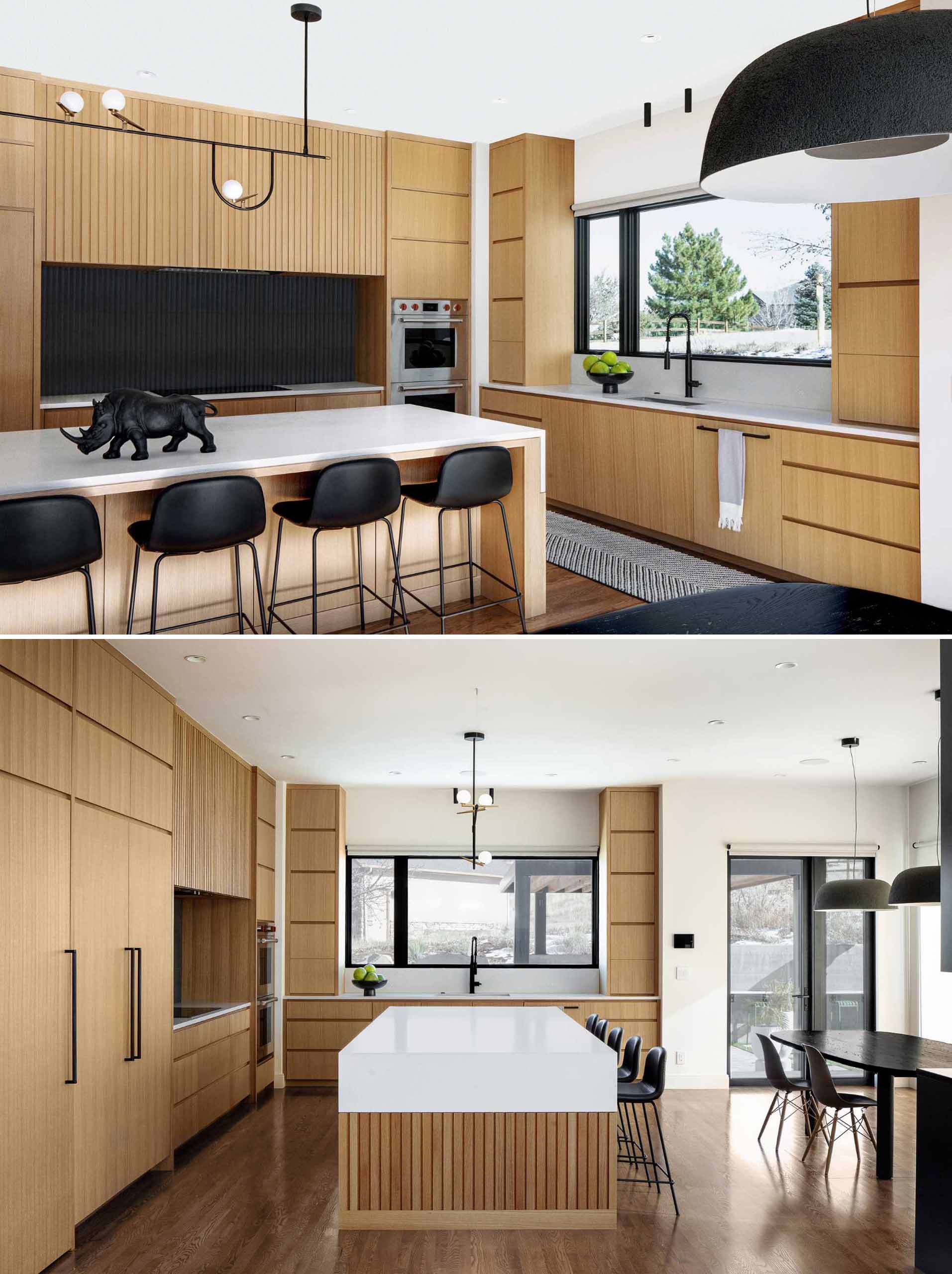 A modern kitchen with an island includes rift-sawn white oak veneer cabinets and concrete-finish quartz countertops. 