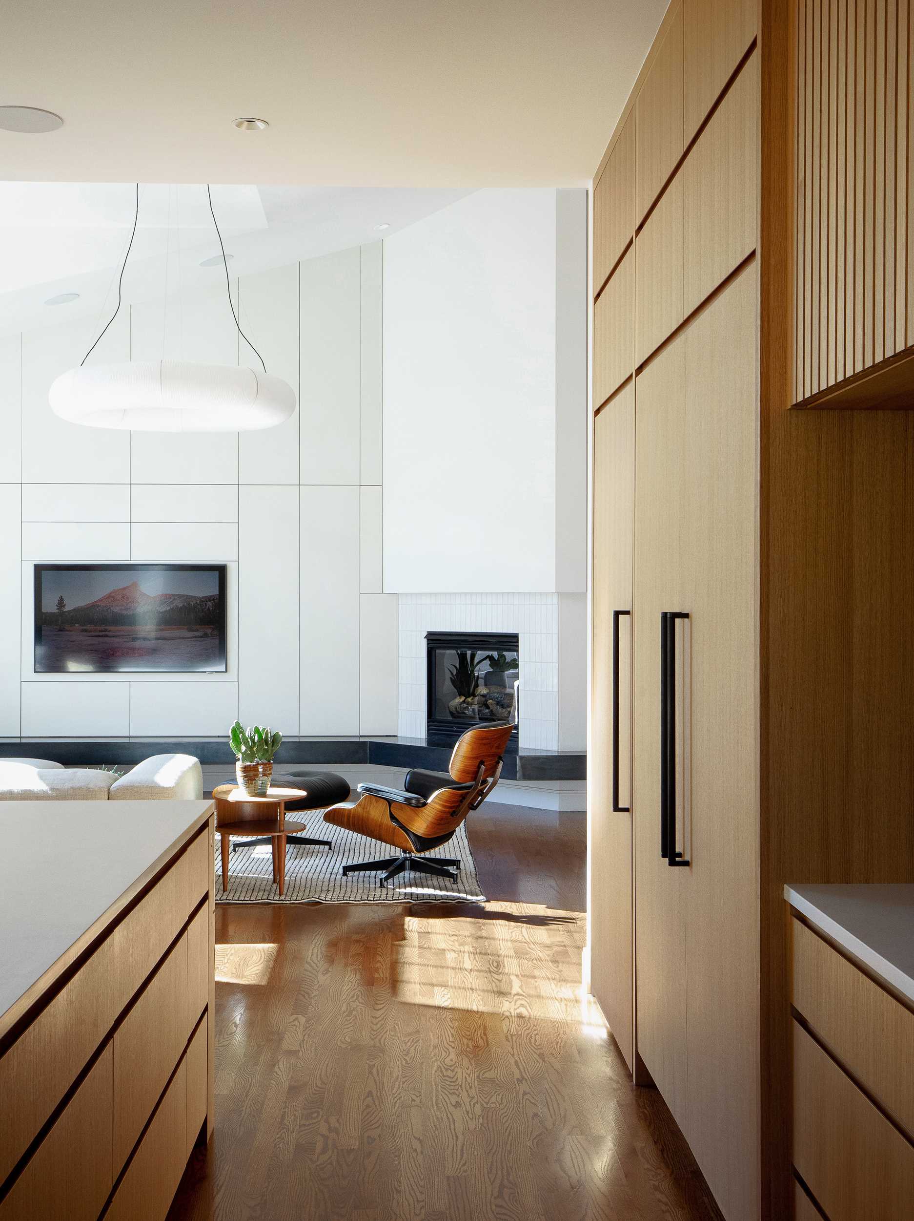 A modern kitchen with an island includes rift-sawn white oak veneer cabinets and concrete-finish quartz countertops. 