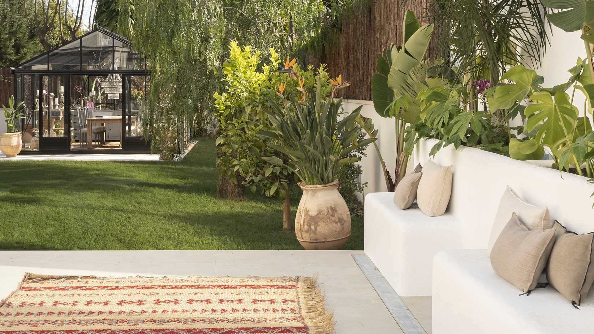 A contemporary garden includes a Nordic-inspired greenhouse, and seating with built-in planters.