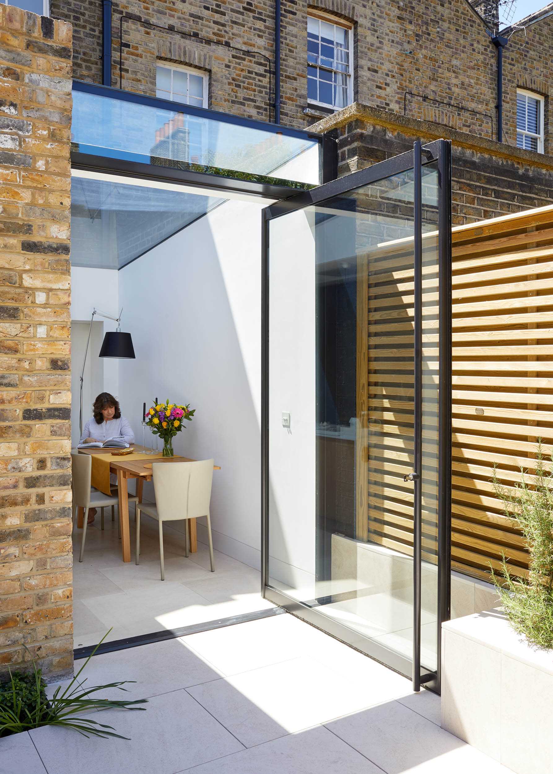 A large pivoting glass door connects the rear addition to the patio, garden, and studio, and at the same time allows natural light inside the home.