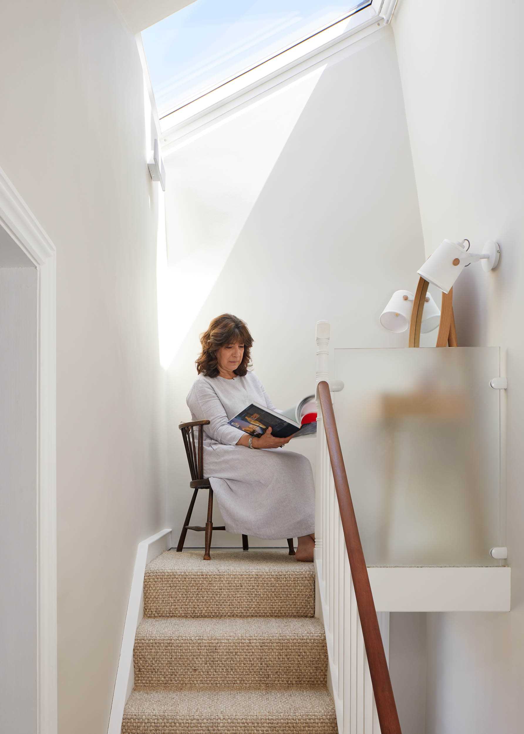 A small reading nook and vanity under a skylight at the top of the stairs.