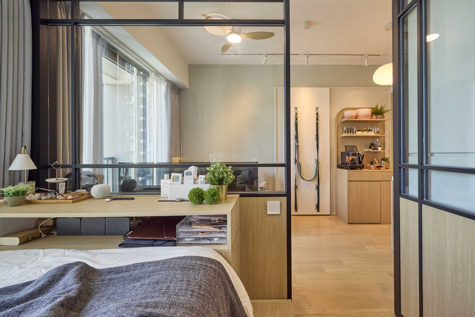 In this small apartment, instead of a standard concrete wall separating the bedroom from the living room, there's a framed panel wall glazed in the upper part, with a wooden lower part. 