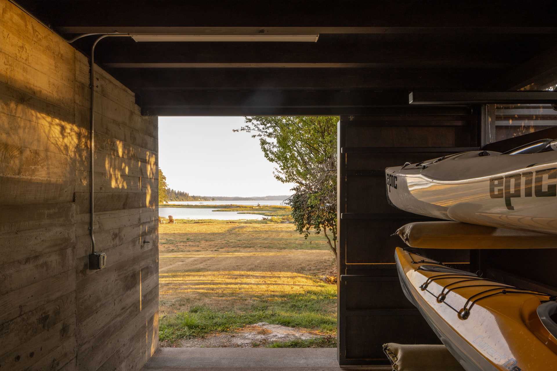 A modern boathouse with storage and a large sliding door.