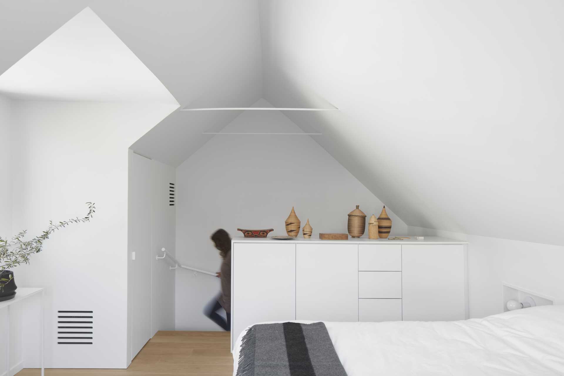 The bedroom of a small laneway house includes a closet and a dresser.