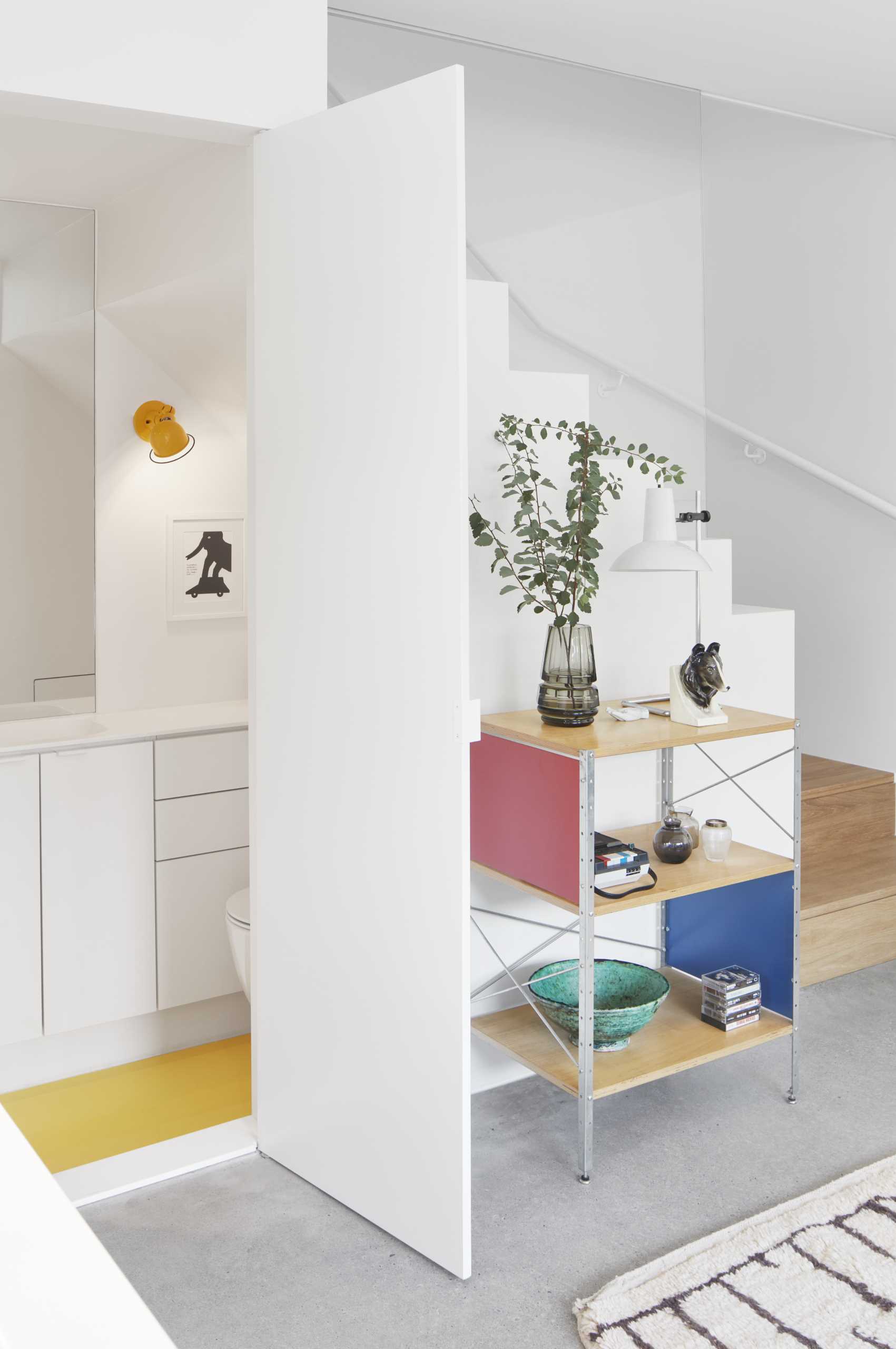 This small bathroom includes a pop of color with a yellow floor, as well as a toilet, vanity, and a walk-in shower.