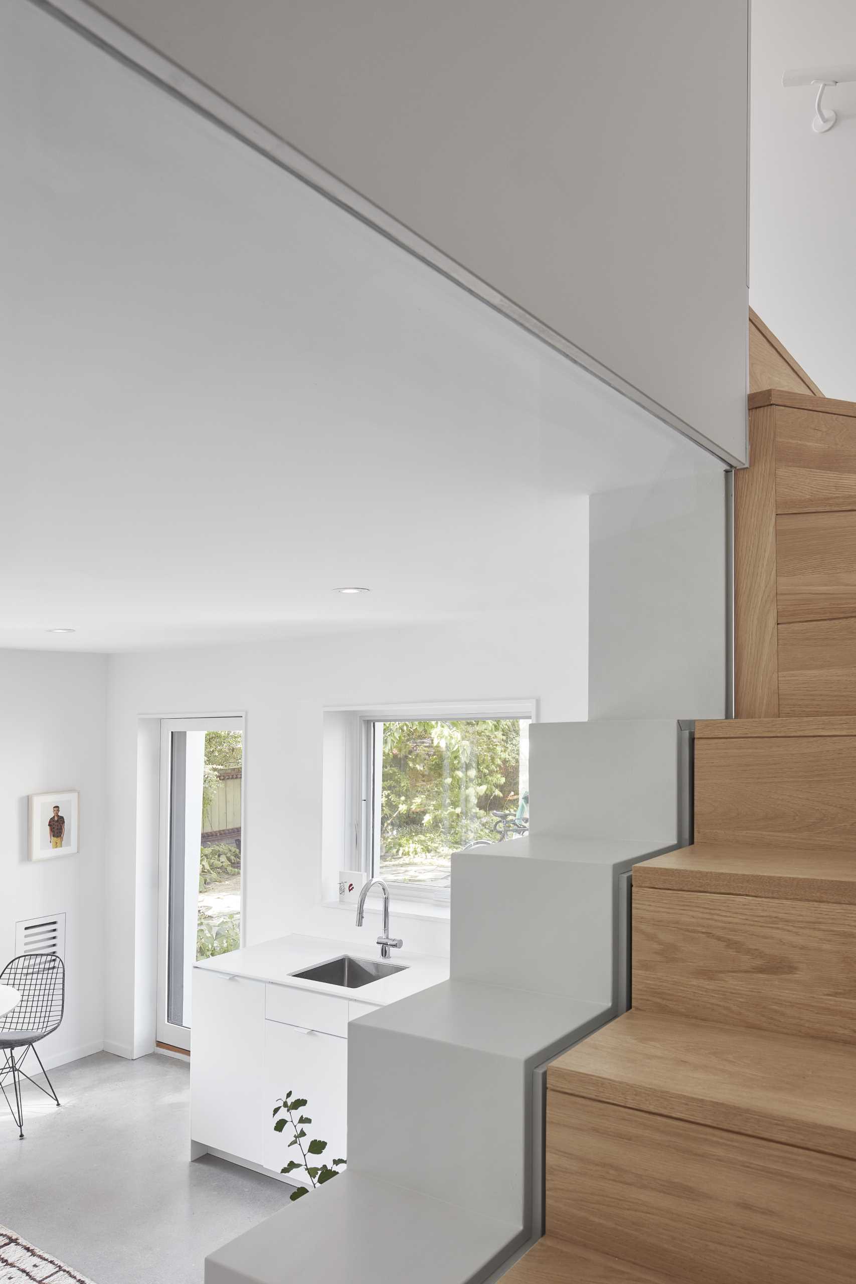 A small laneway house with wood stairs that lead to a bedroom.