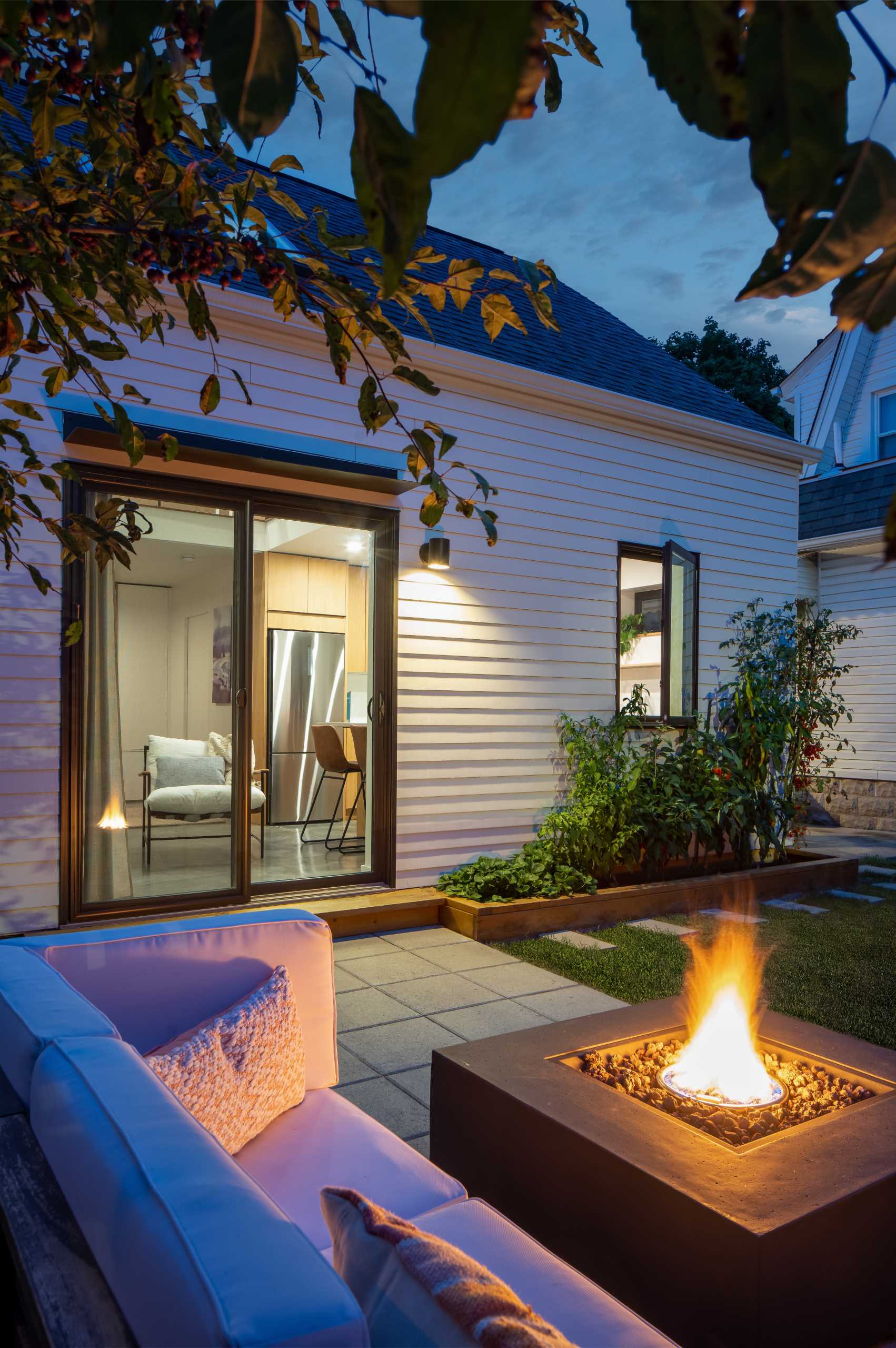 A patio where pavers and a wood accent wall have been used to create a lounge area with a fire table.