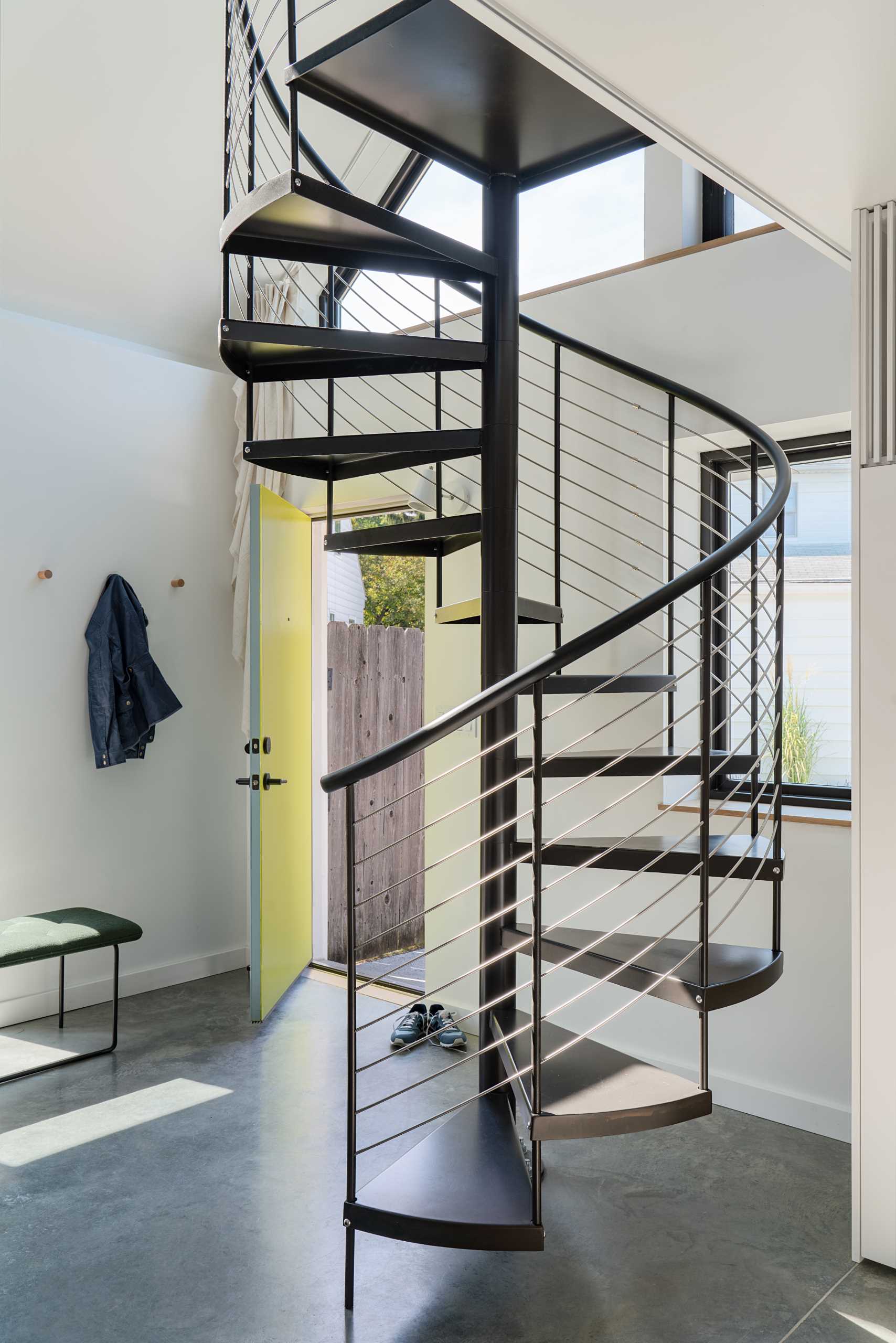 Black spiral stairs lead to a lofted home office and lounge.