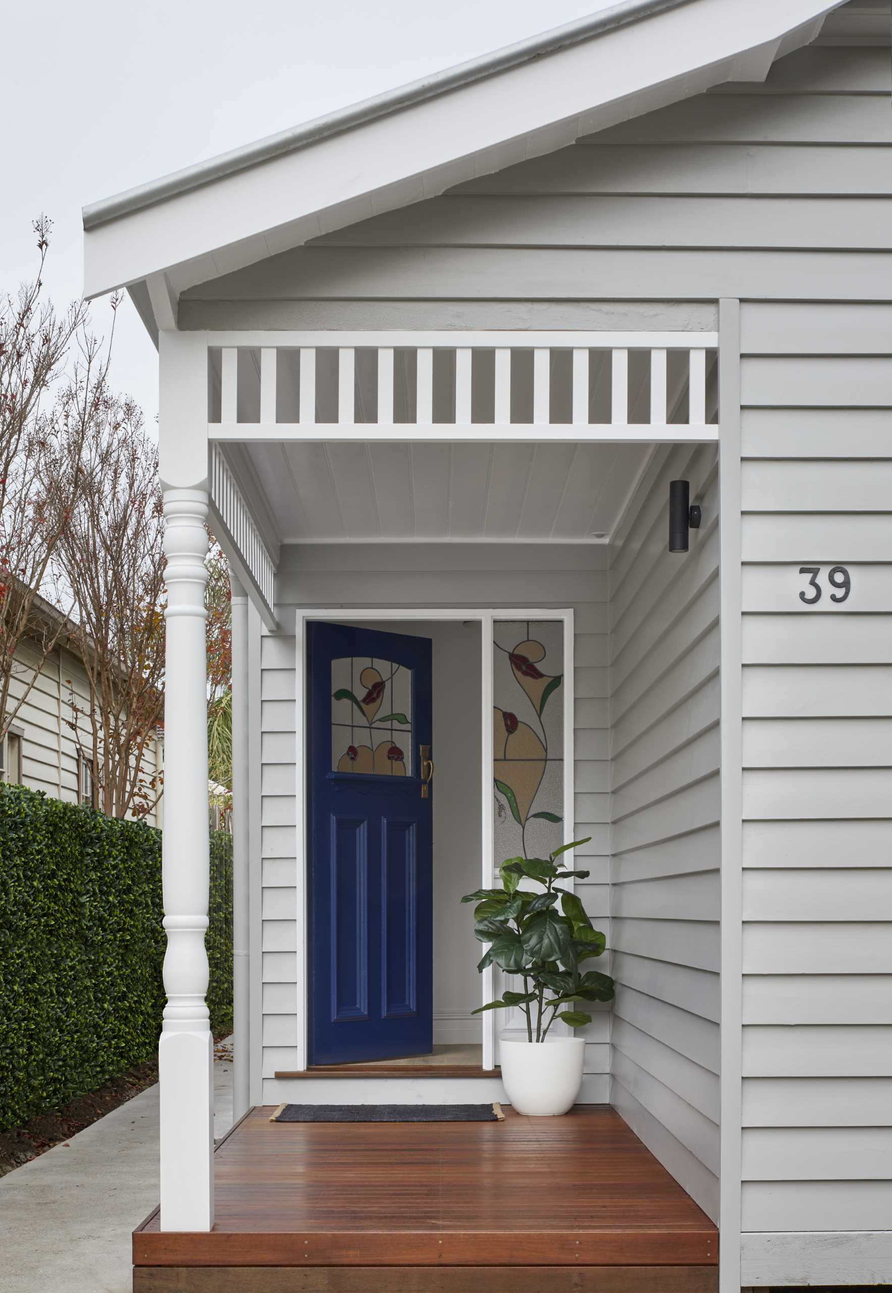 The original facade of this home was restored, weatherboards were replaced, and new fretwork and posts were installed and repainted. New decking on the front porch was also added, and the original front door with stained glass was kept and restored.