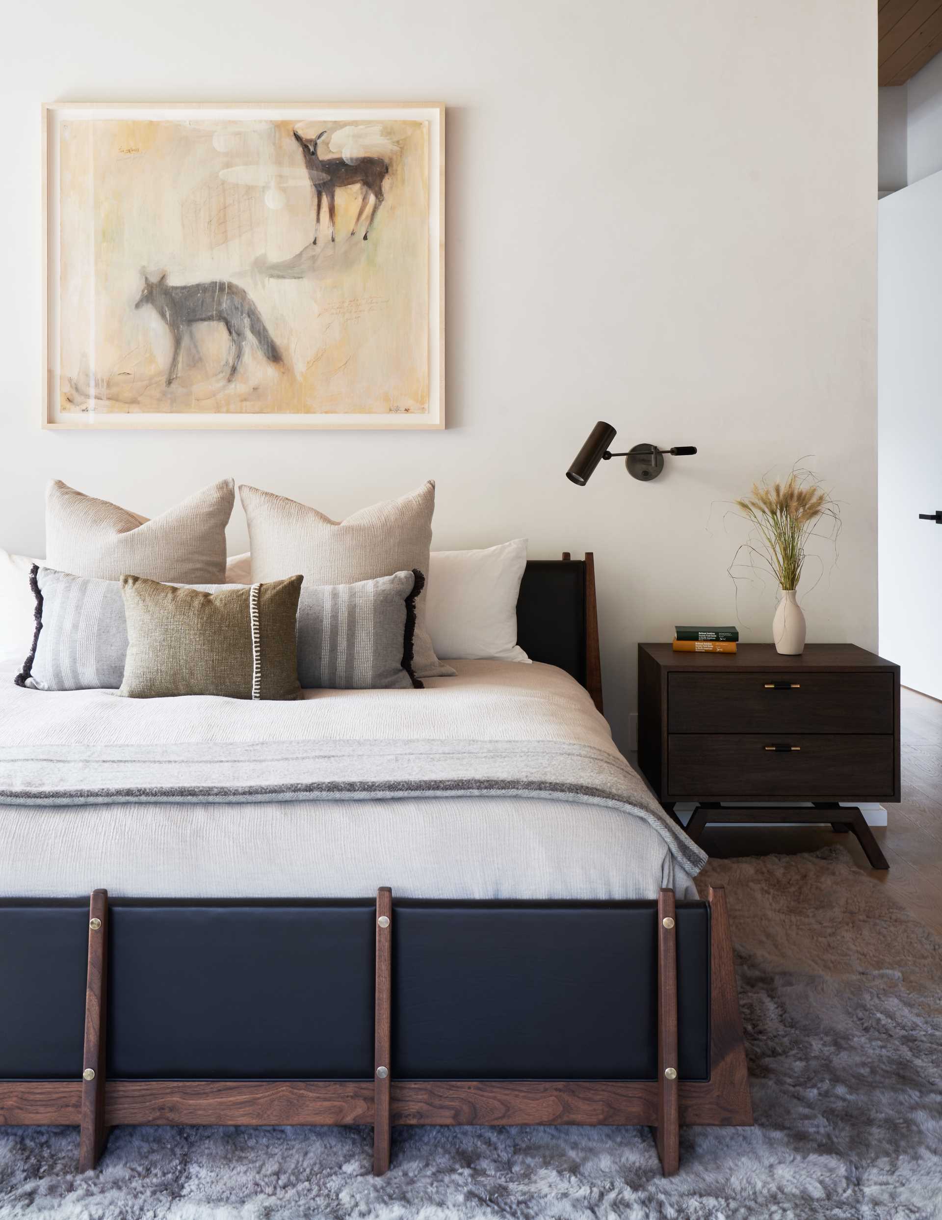 A contemporary bedroom with a black bed and wood frame.