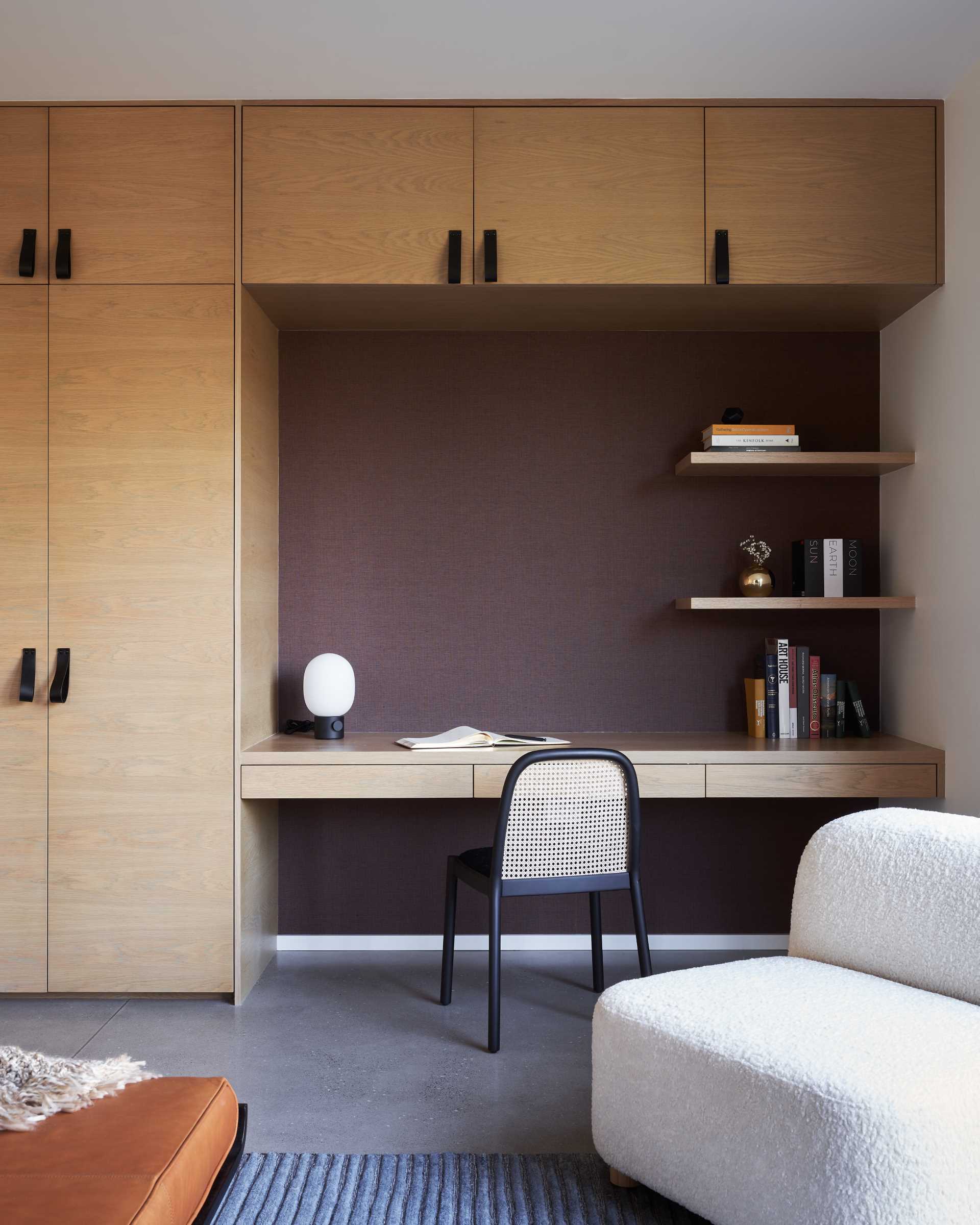 A wall of cabinetry with leather pulls, includes a floating desk and matching shelves.