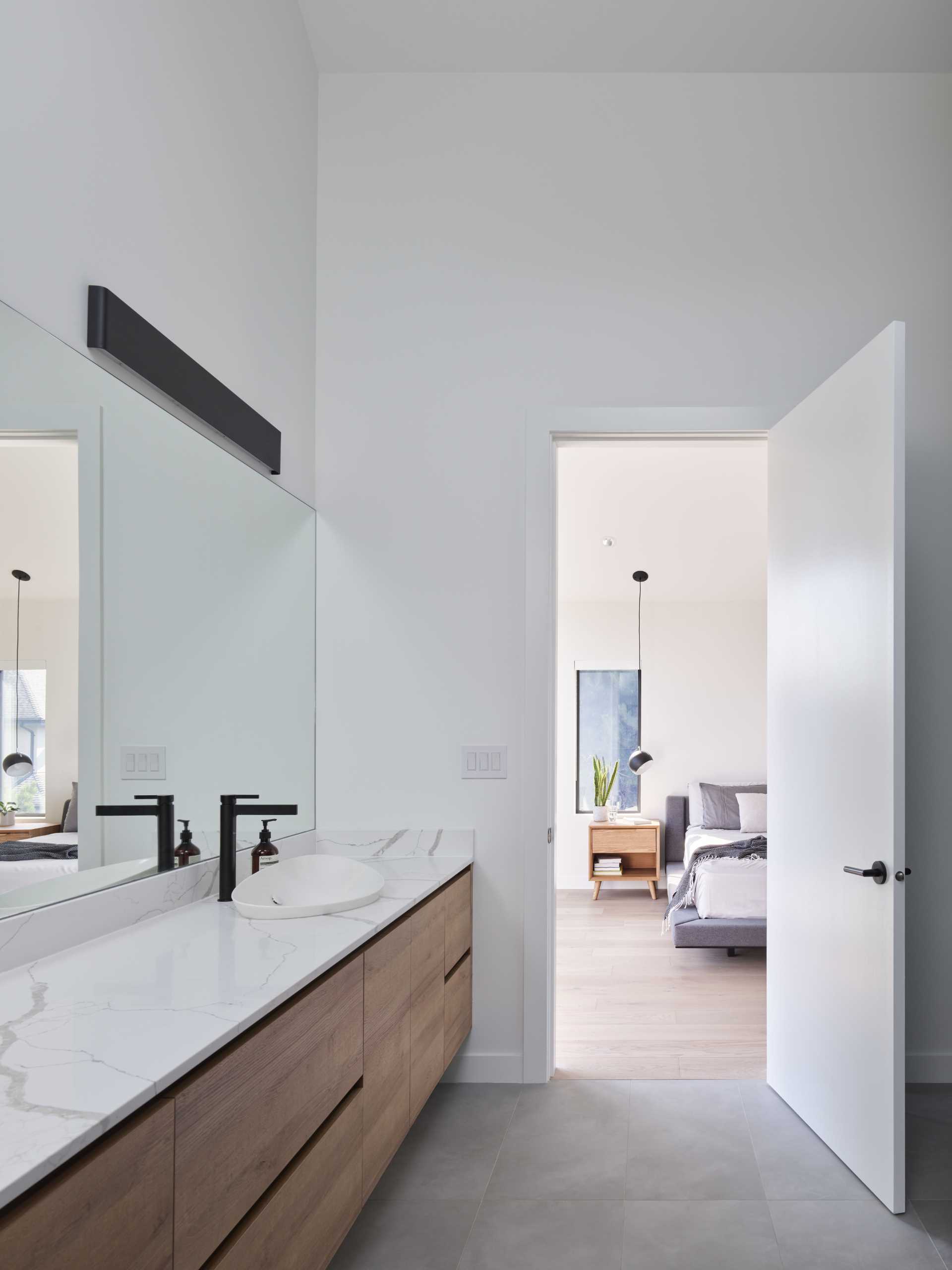In this modern en-suite bathroom, there's a double vanity, a glass-enclosed walk-in shower, and a freestanding bathtub by the window.