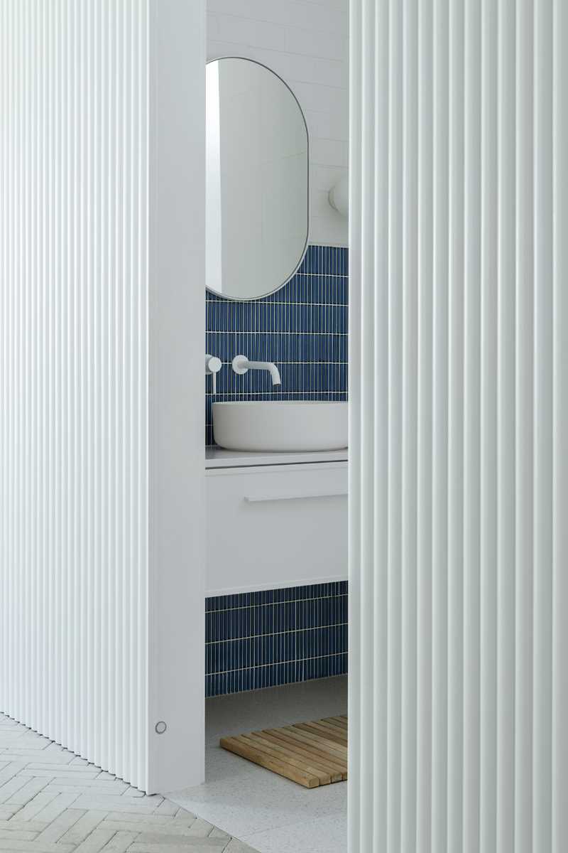 A modern bathroom with blue tiles, a floating vanity, and white bricks.