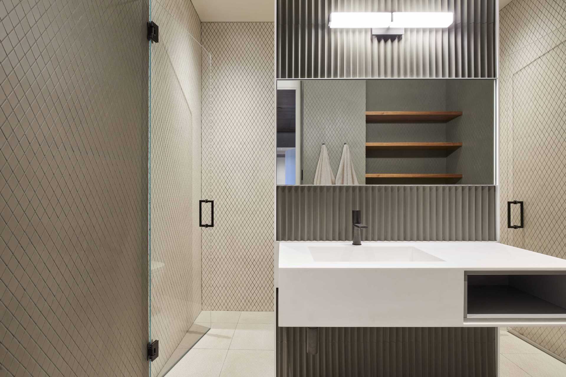 A modern bathroom with tiled-covered walls and a textured element behind the vanity and mirror.