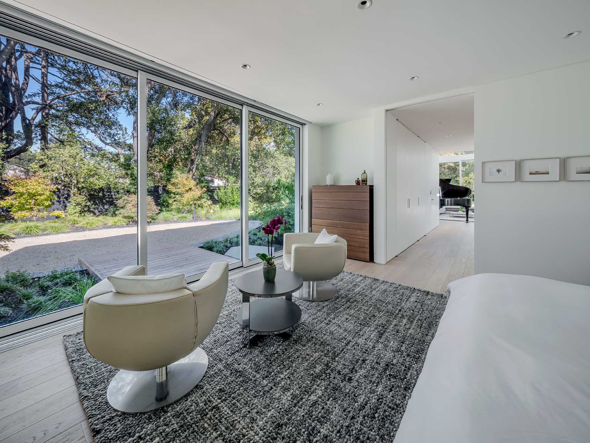This modern primary suite has a sitting area facing the garden.