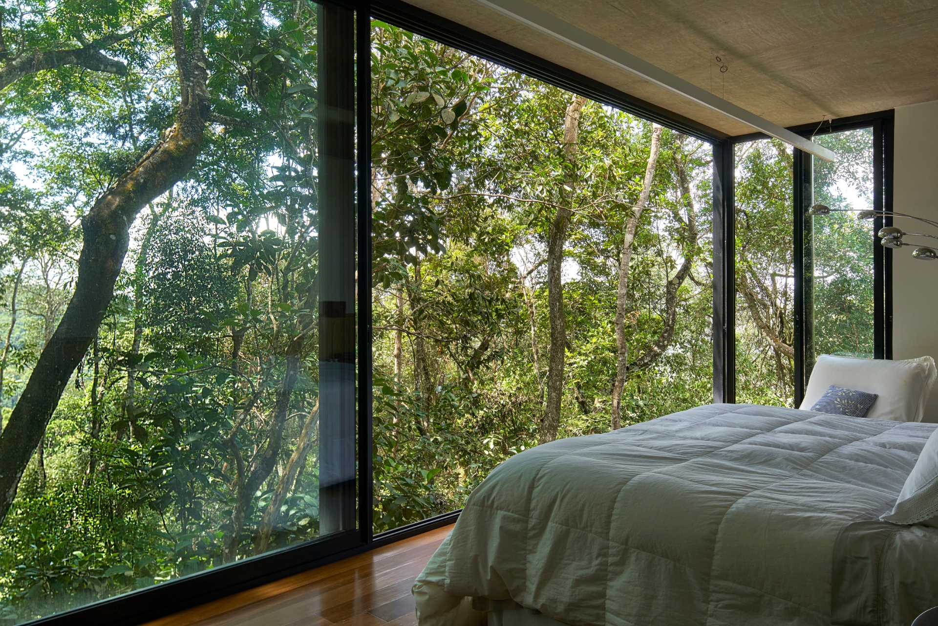 A modern bedroom with floor-to-ceiling windows.