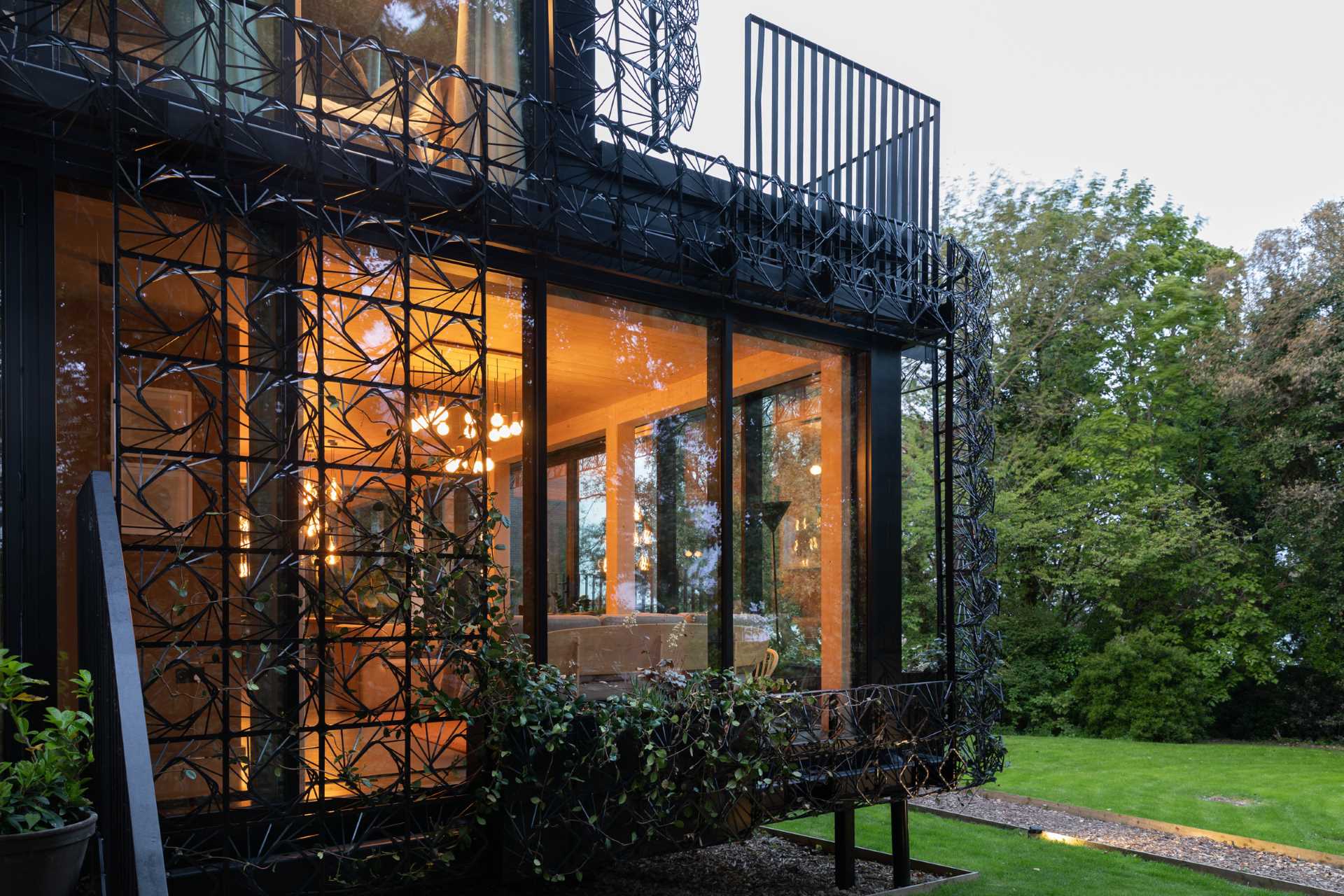 A modern black house with a sculptural facade designed to let plants grow on the exterior over time.