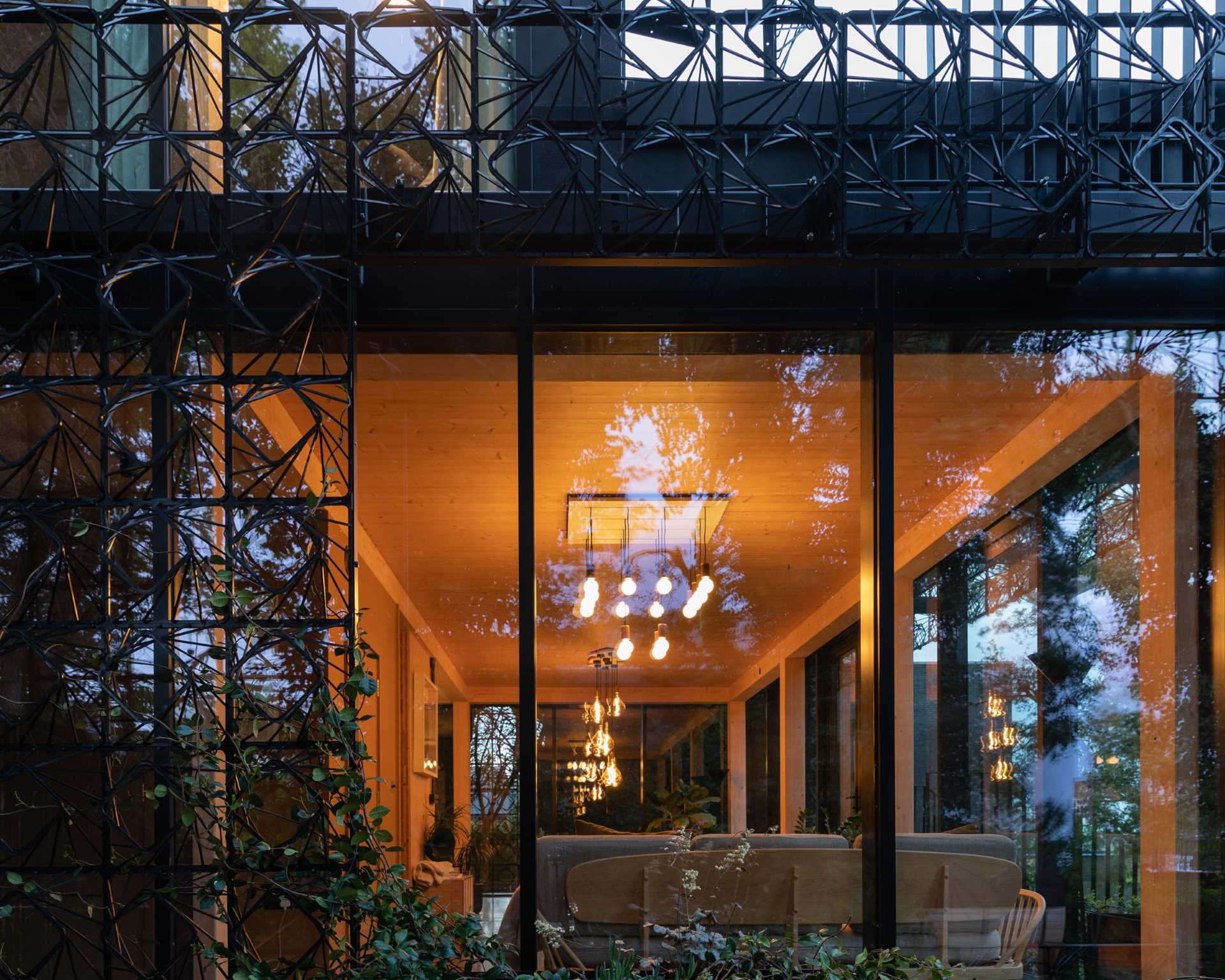 A modern black house with a sculptural facade designed to let plants grow on the exterior over time.