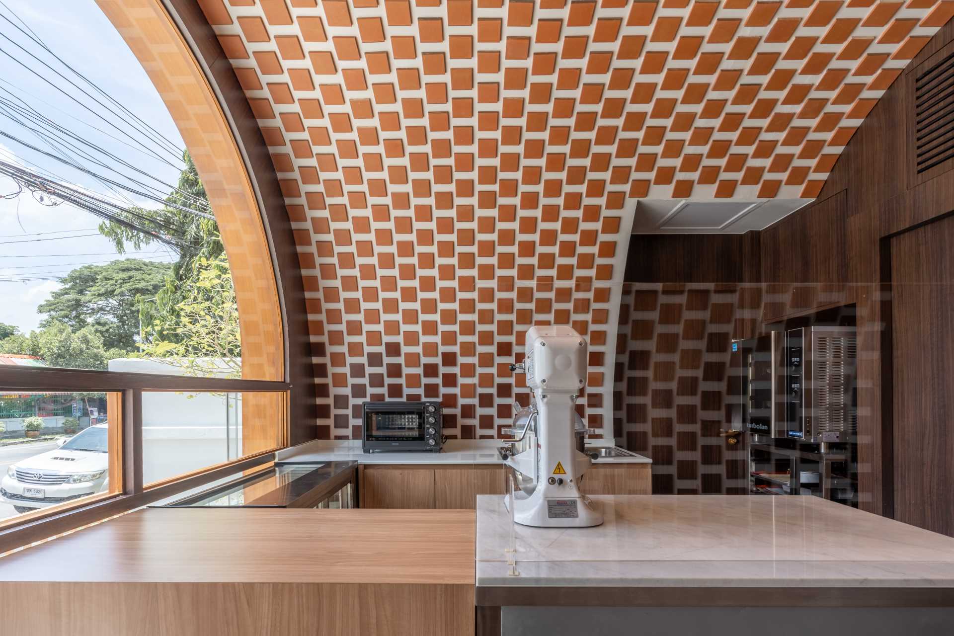 A small cafe with facade that features an arched window detail, and an interior with gradient tiles.