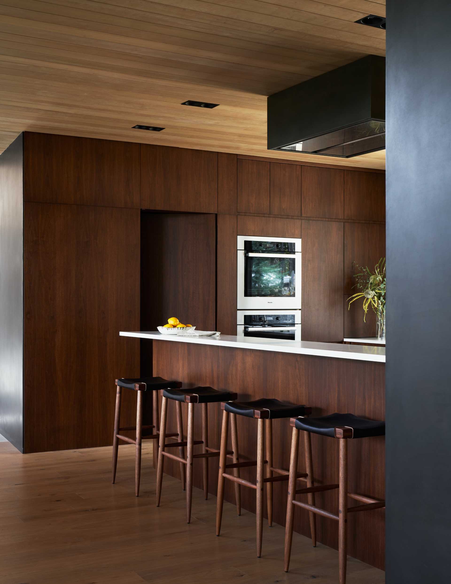 A modern kitchen with dark walnut cabinets and white countertops.