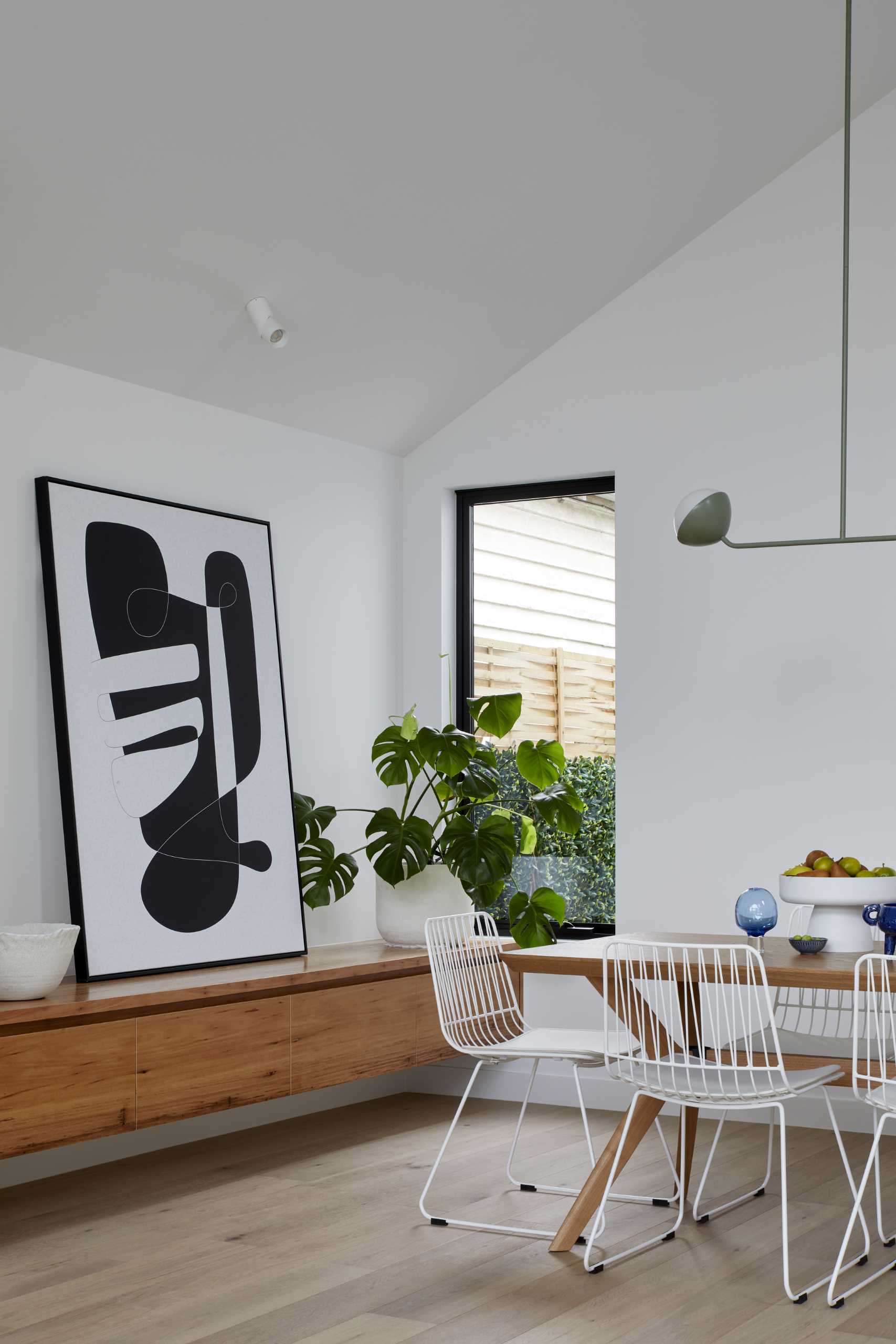 A modern open plan dining room includes a floating wood cabinet.