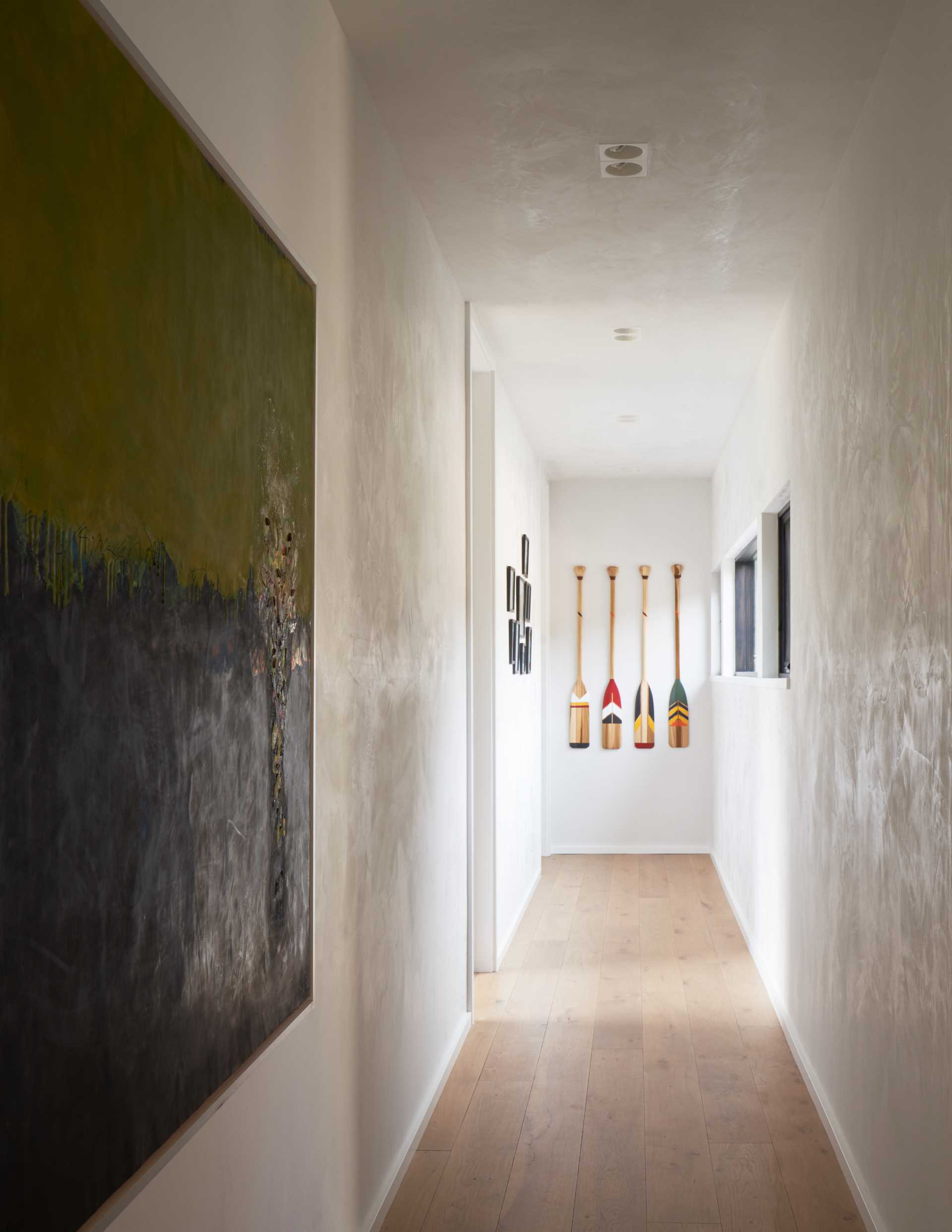 A contemporary hallway with artwork and wood floors.