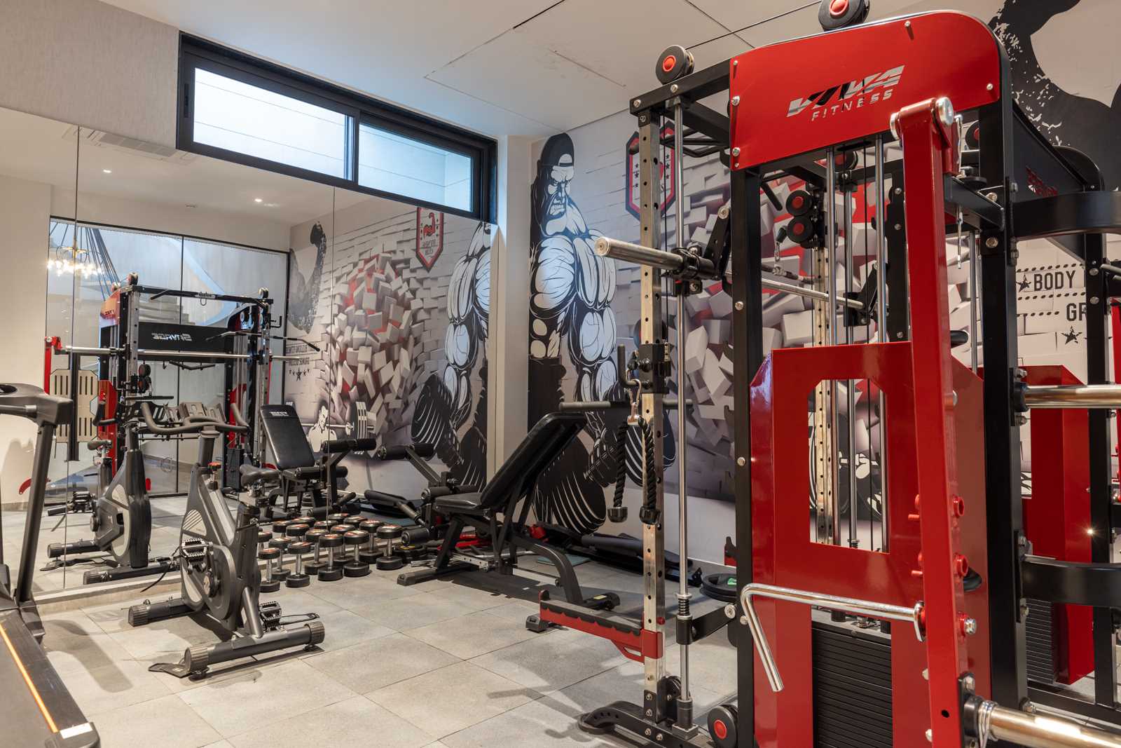 In this home gym, black and red are the chosen colors, and a large mural covers the wall.