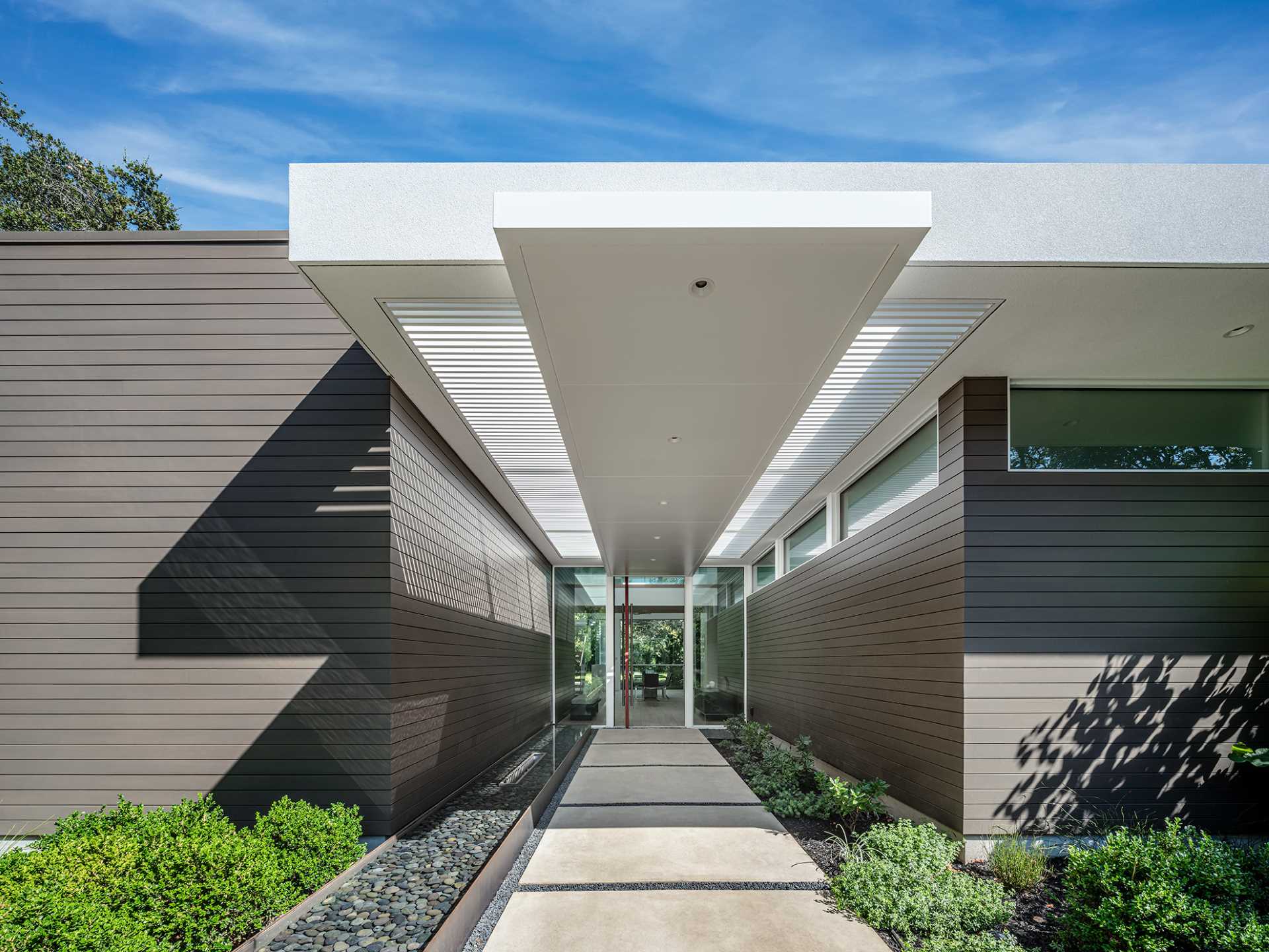 A long, linear infinity-edge water feature terminates at the front door.