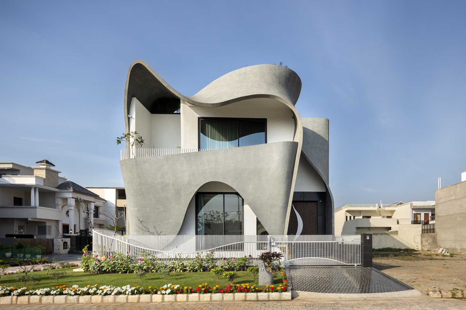 A modern house with a sculptural facade that features ribbon-inspired free-flowing concrete.