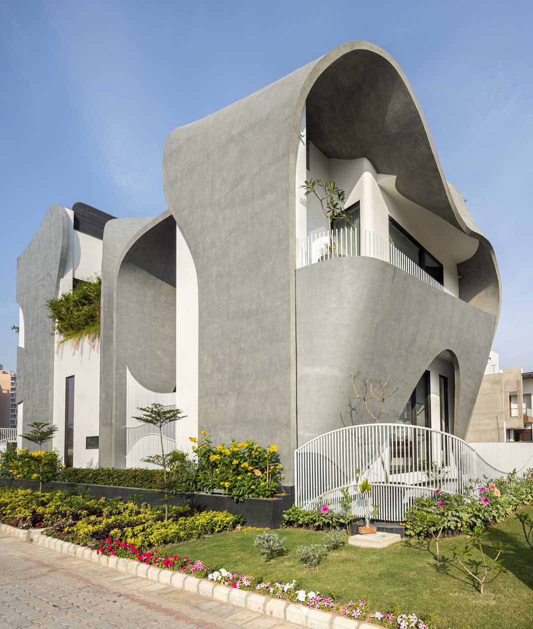 A modern house with a sculptural facade that features ribbon-inspired free-flowing concrete.