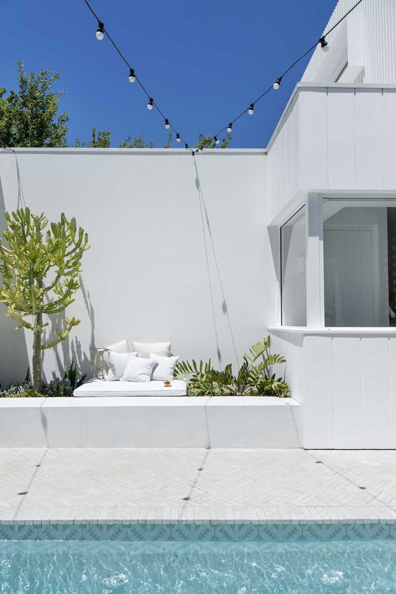 Wall surrounding a swimming pool include planters and a seating area.