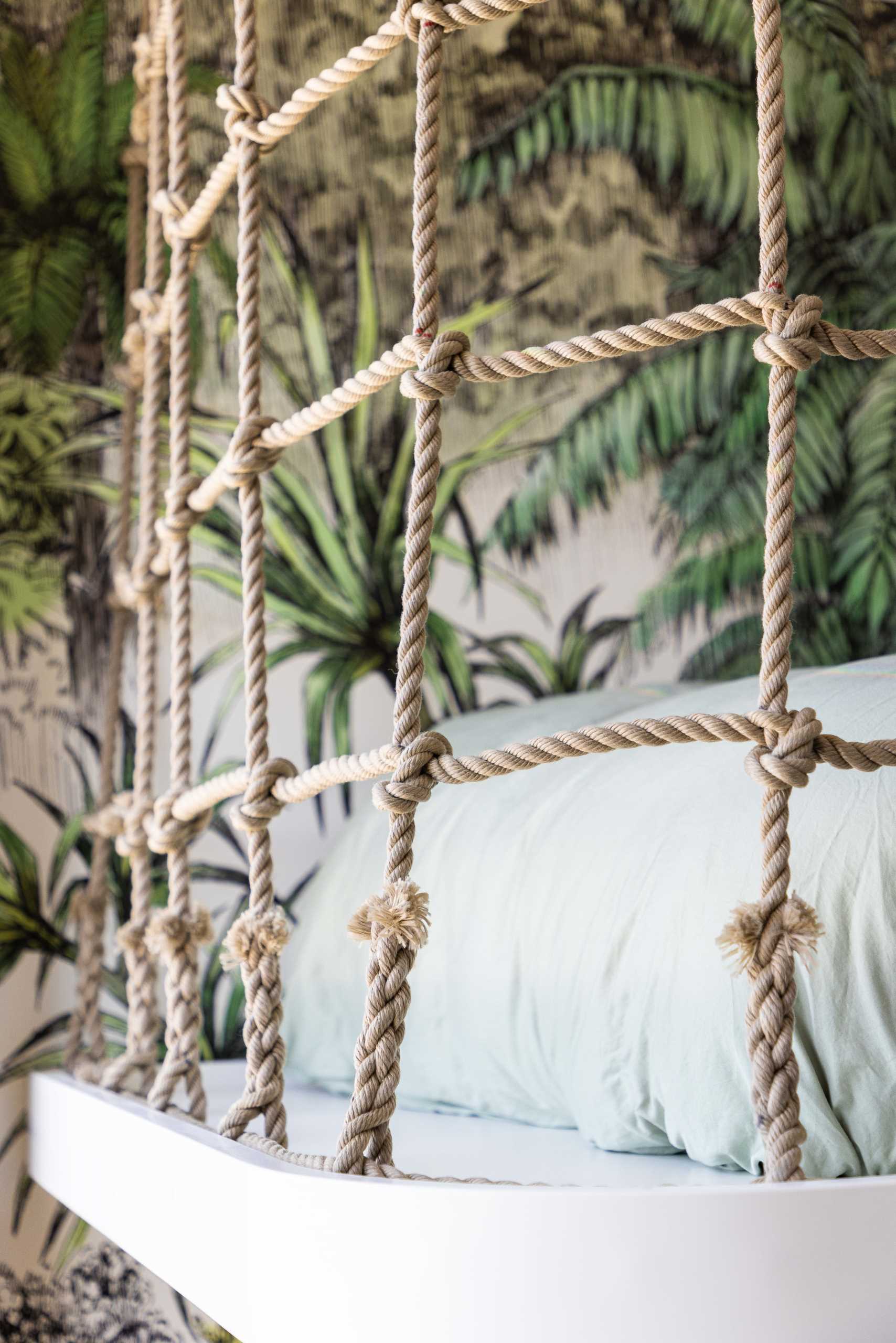 A modern jungle-themed bedroom for two brothers includes bunk beds, rope work, stairs with storage, and tree-top wallpaper.