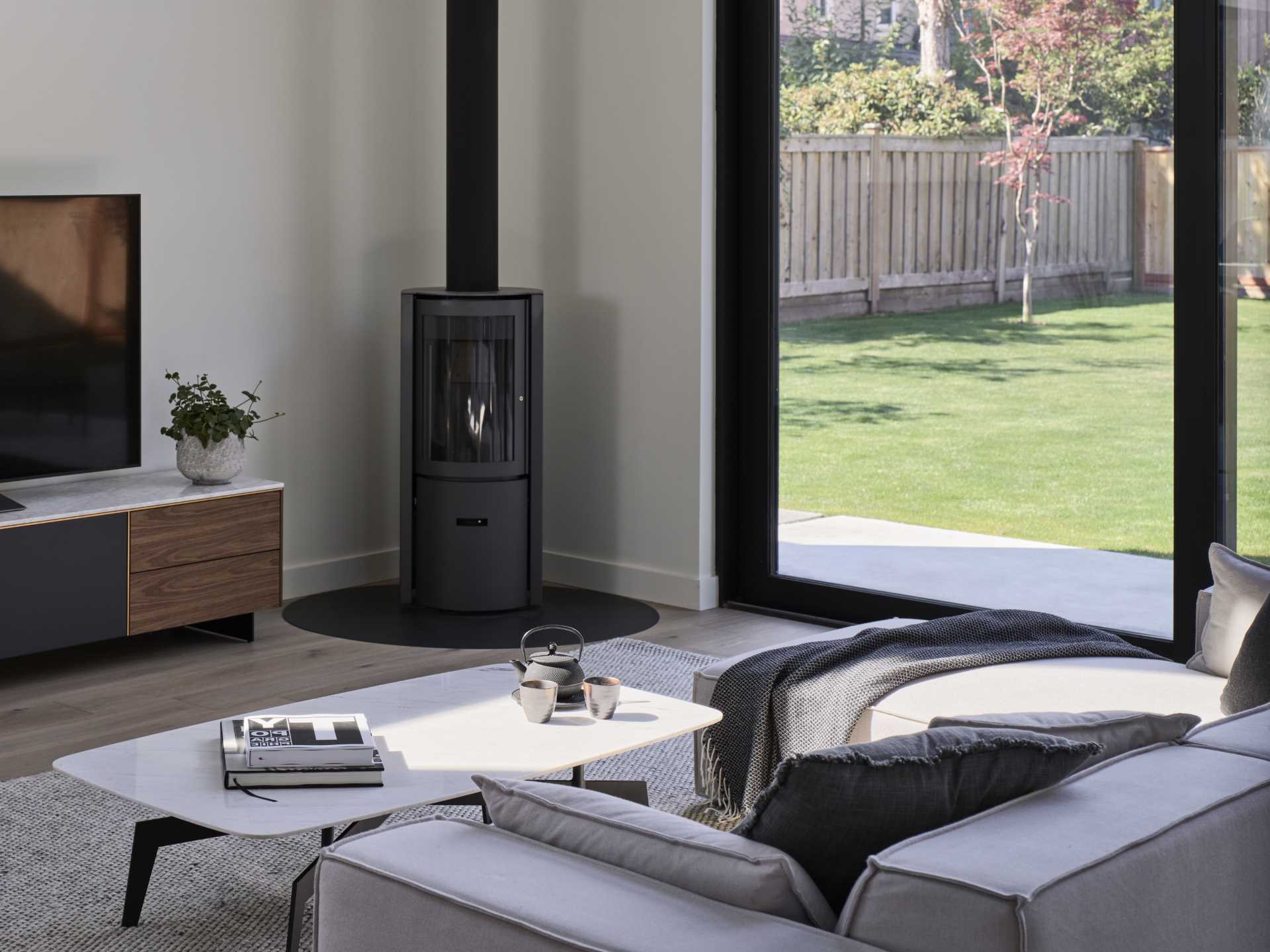 A contemporary living room with a black fireplace in the corner.