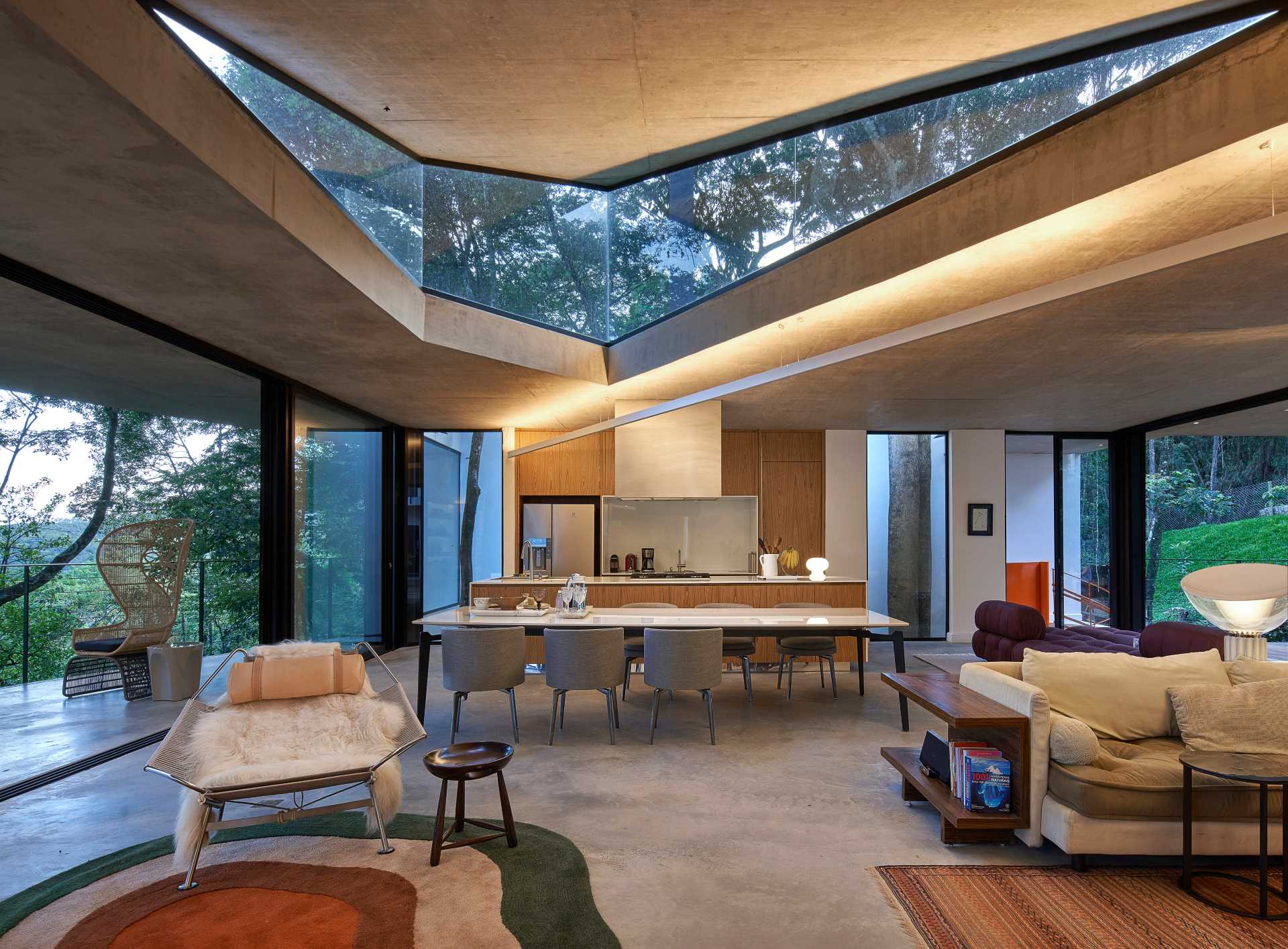 Inside this modern home, the angular design is highlighted by lighting and window shapes, while the living, dining, and kitchen all share the same open space.