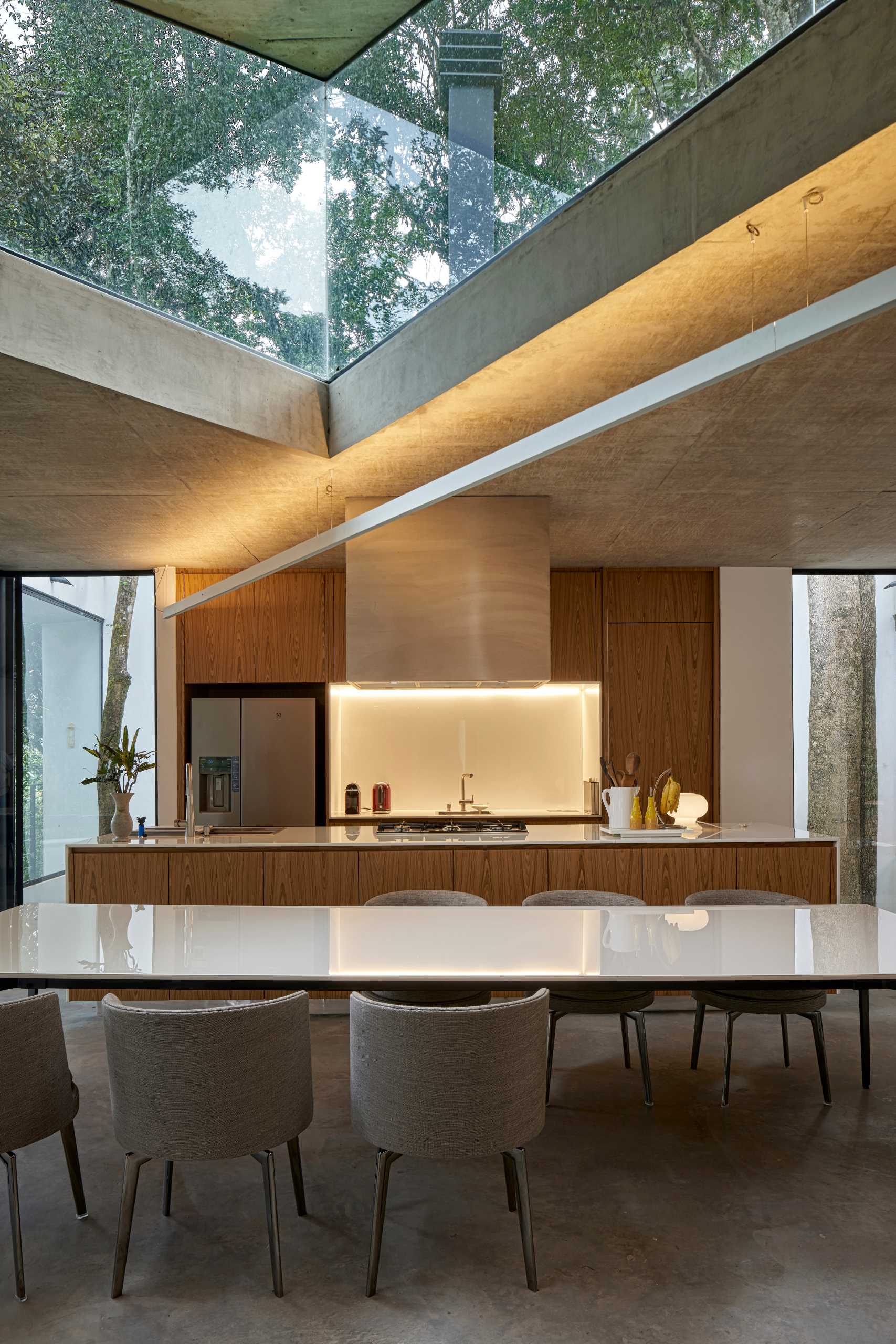 Inside this modern home, the angular design is highlighted by lighting and window shapes, while the living, dining, and kitchen all share the same open space.