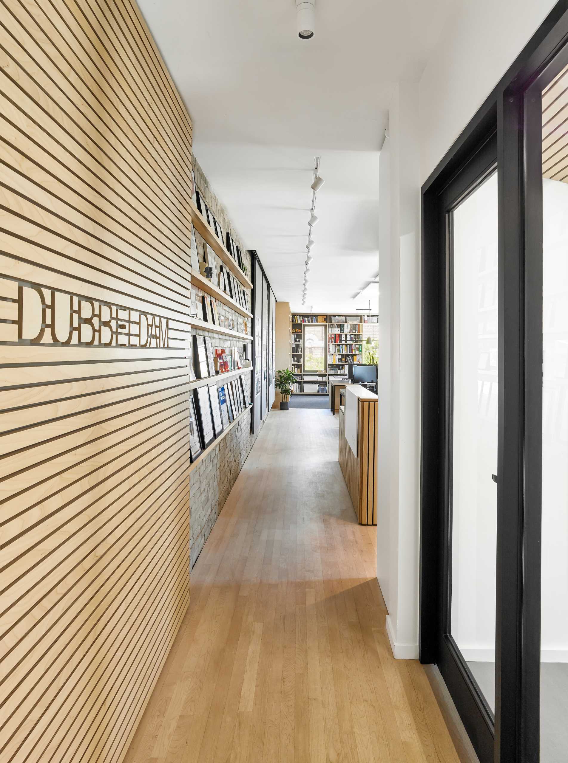 A modern office with wood slats and a white Corian waterfall panel that greets visitors with an inscribed “hello” at the reception desk.