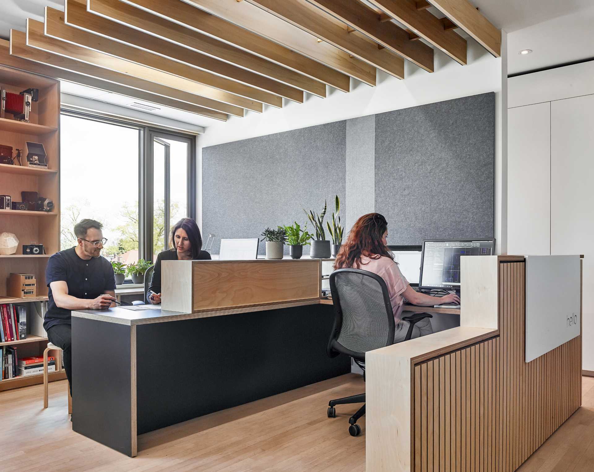 The grey wall and ceiling-mounted eco-felt panels provide acoustical benefits in this office.