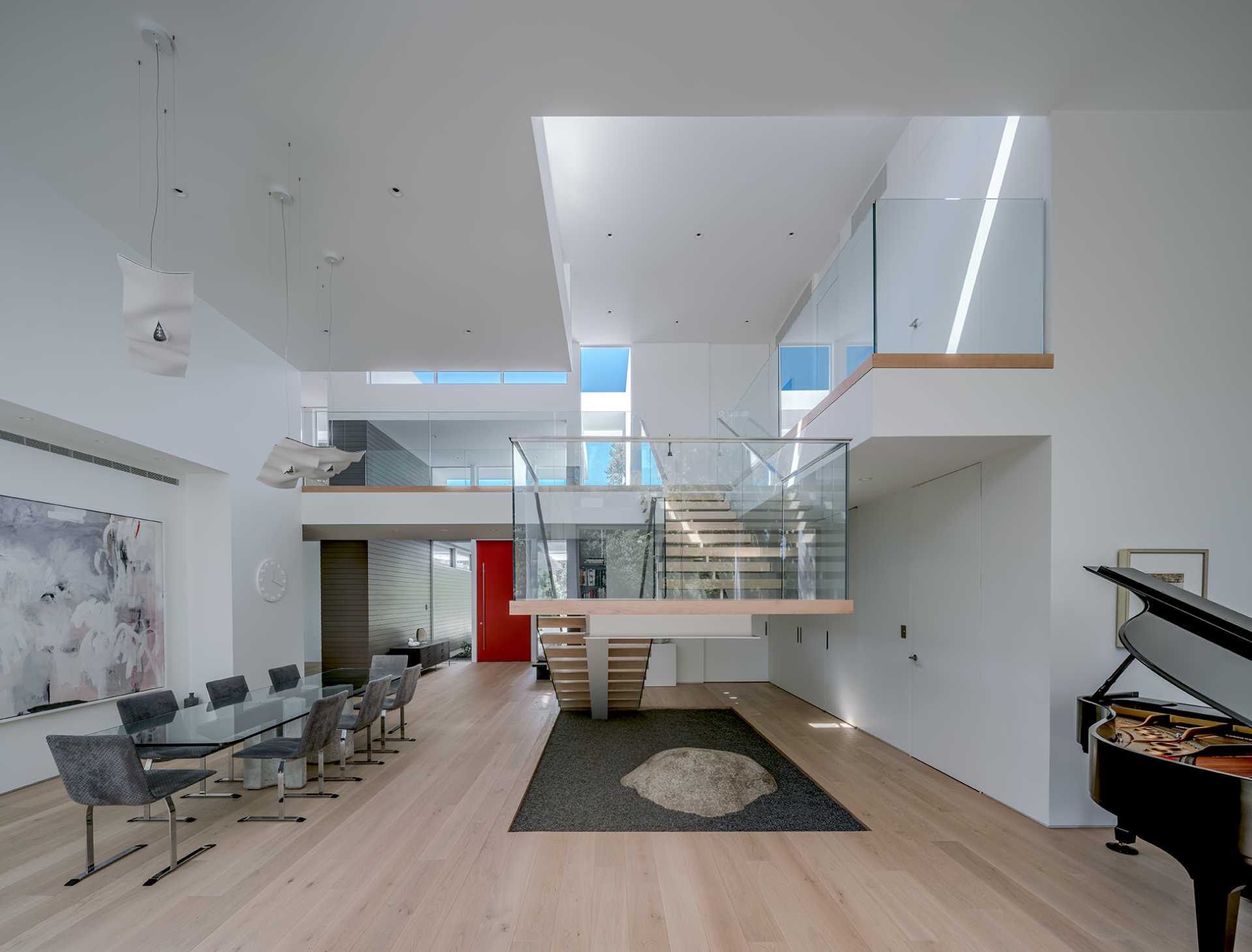 A modern entryway opens up into the dining area, that's home to a long glass table and high ceilings.