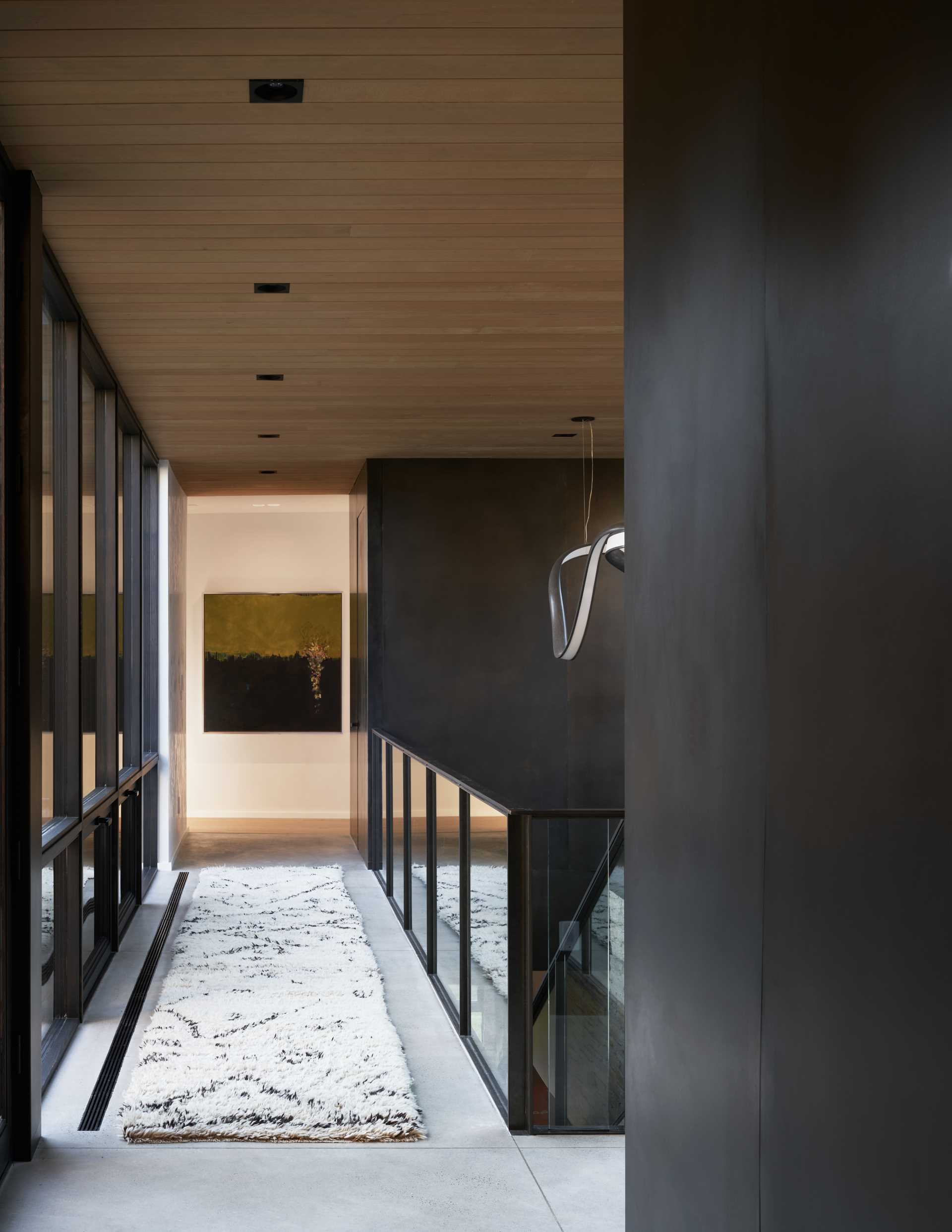 A double-sided glass corridor on the upper level connects various areas of the home, creating a transparent zone in the home’s core and inviting the outside in.