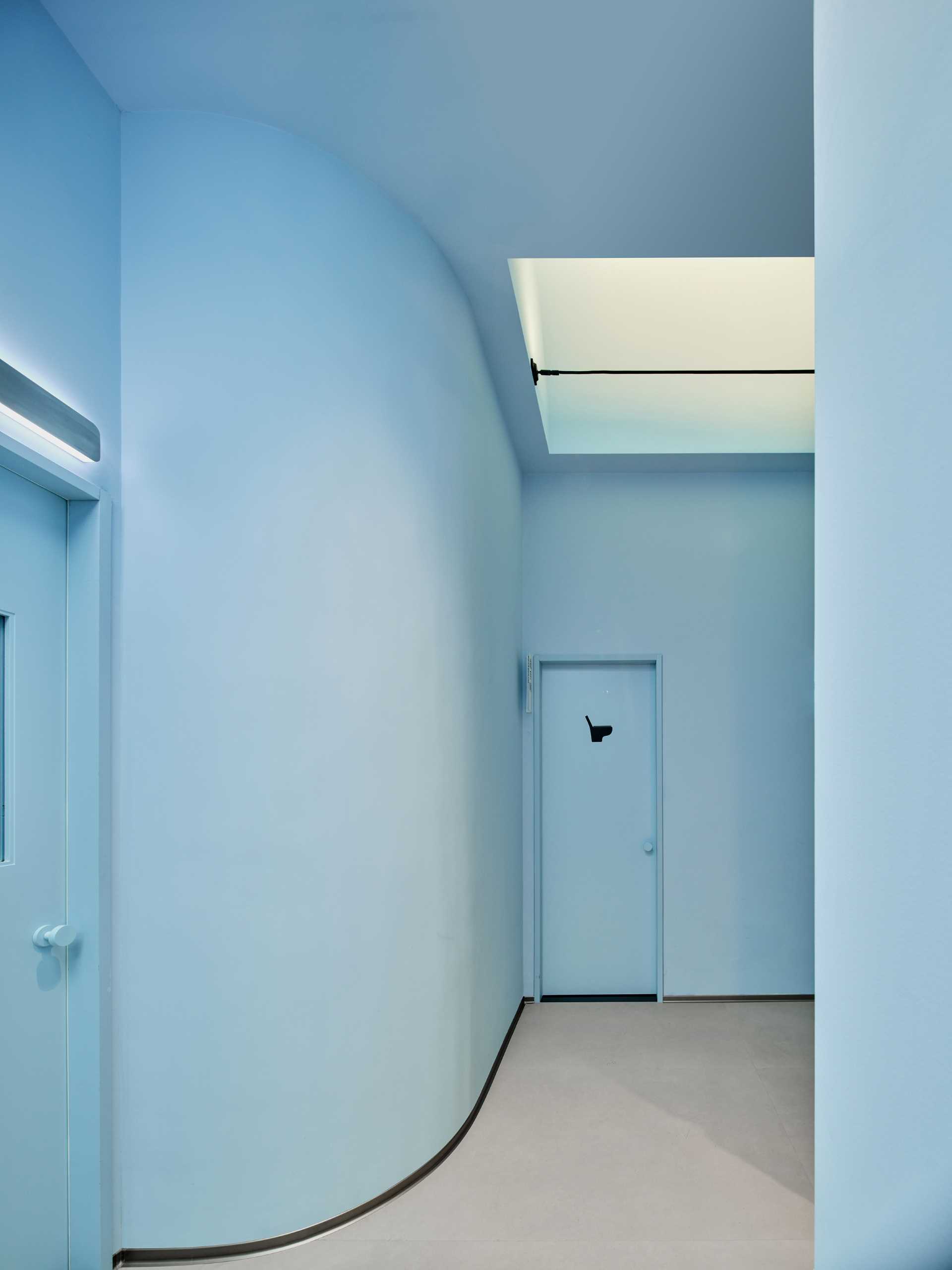 A light blue hallway leads to the various treatment rooms of this modern skincare center.