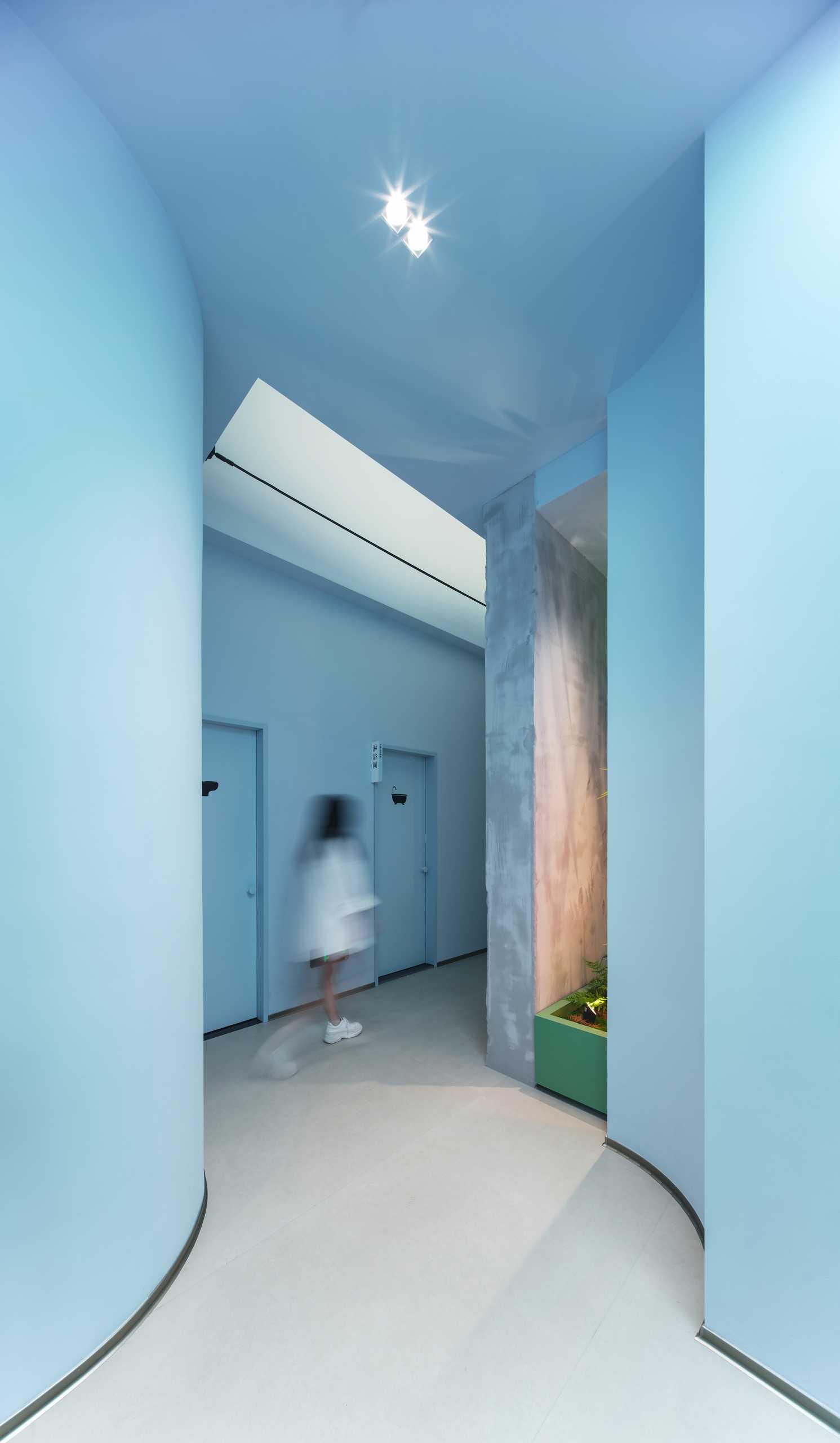 A light blue hallway leads to the various treatment rooms of this modern skincare center.