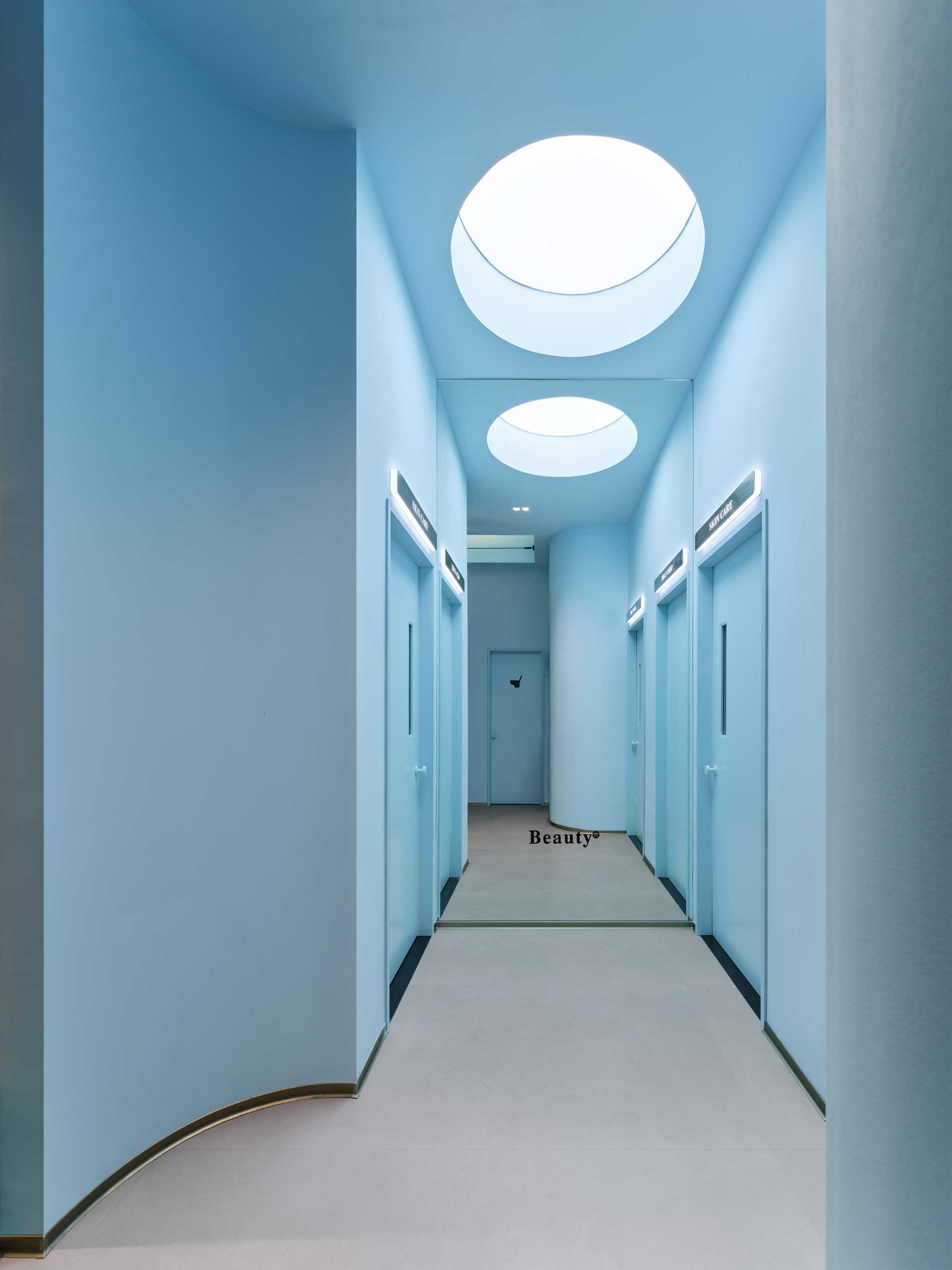 A light blue hallway leads to the various treatment rooms of this modern skincare center.
