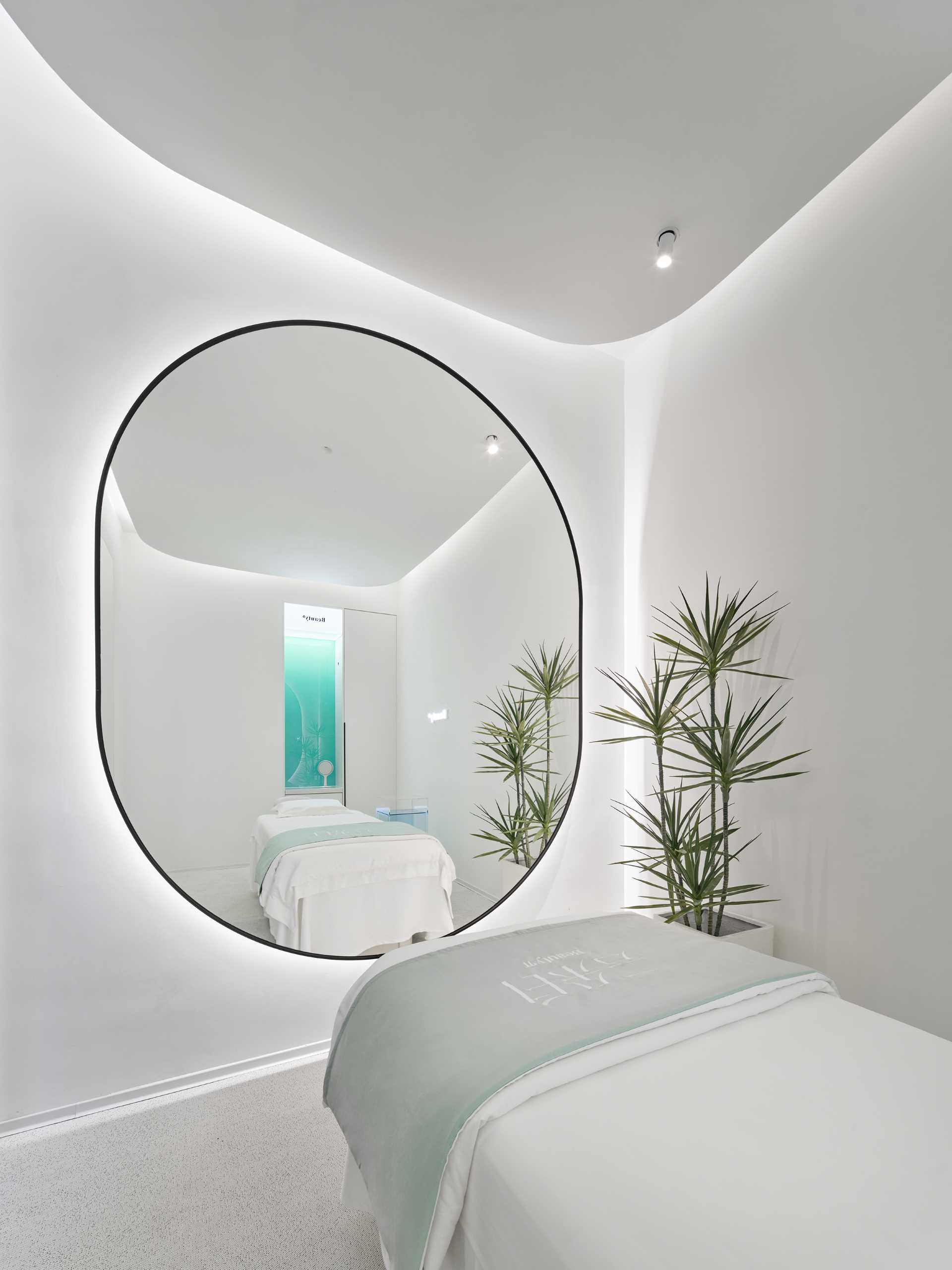 The single-person treatment room has a rectangular layout with a rounded ceiling detail to soften the corners. A large mirror makes the space feel larger, while the opposite wall features a blue-green gradient glass accent.