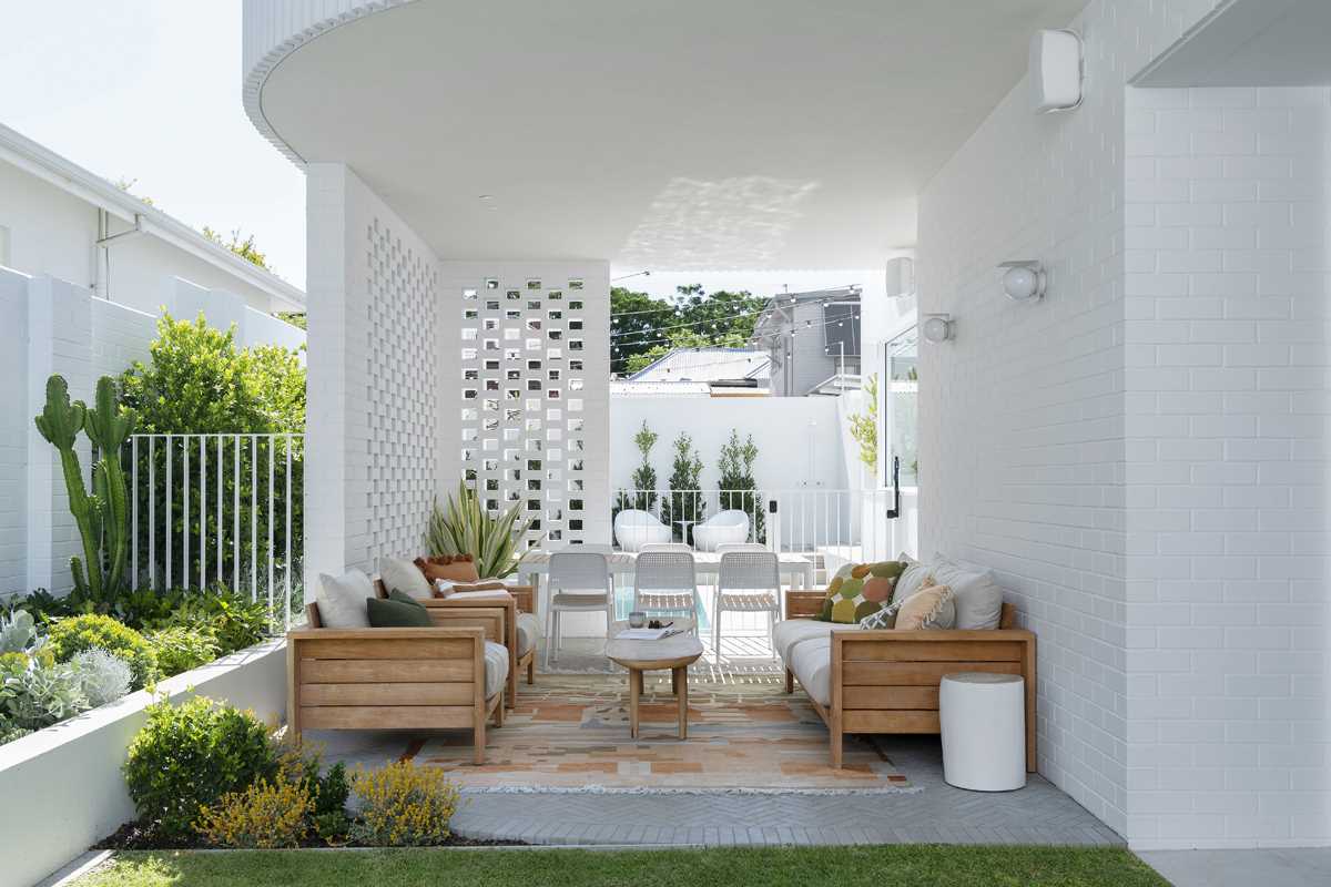 The rear of the home, with its curved design, creates a shaded space underneath that's been furnished as an outdoor lounge and dining area.