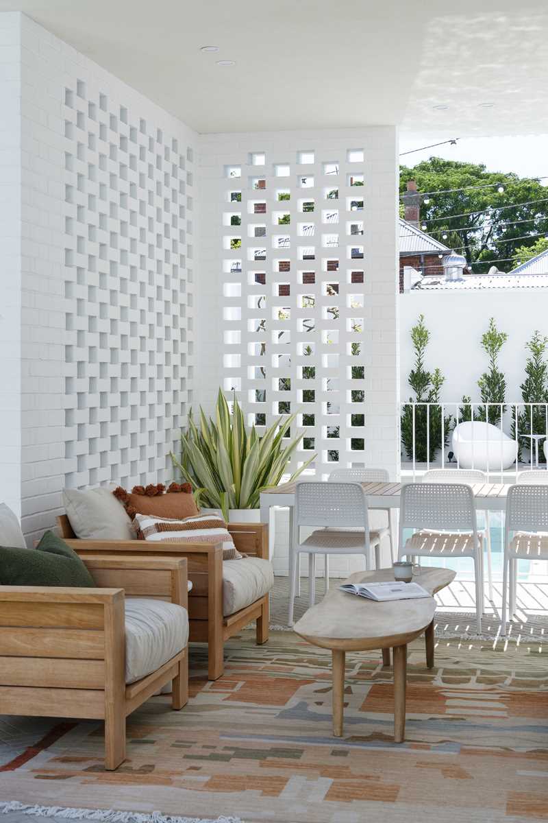 The rear of the home, with its curved design, creates a shaded space underneath that's been furnished as an outdoor lounge and dining area.