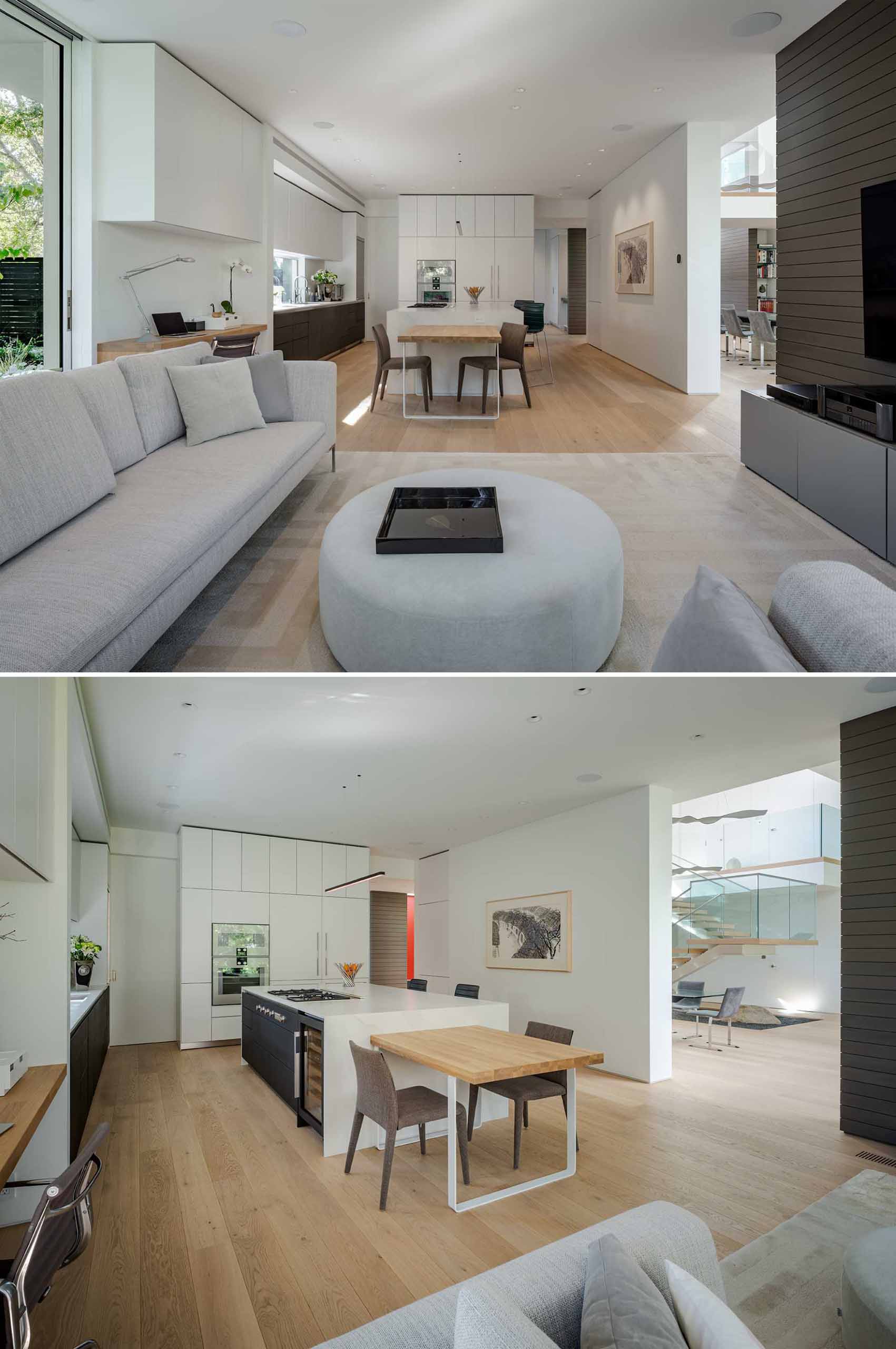 This modern kitchen features both light and dark cabinetry, while a small eat-in area has a wood table that complements the nearby built-in desk.