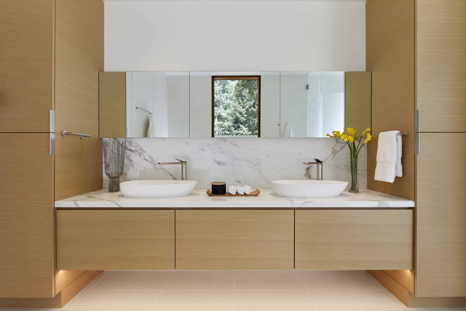 A primary bathroom featuring wood cabinetry, a freestanding bathtub, and a glass-enclosed double shower.