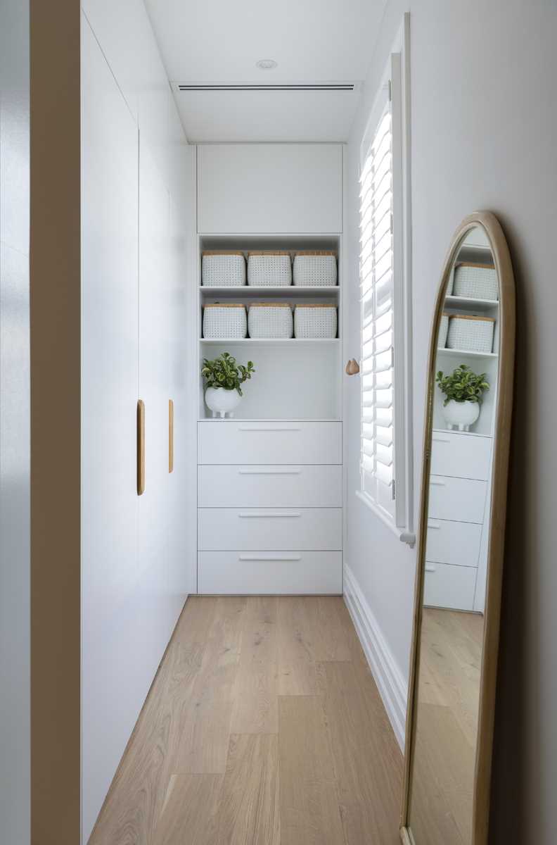 A walk-in closet with white cabinets, drawers, and open shelving.